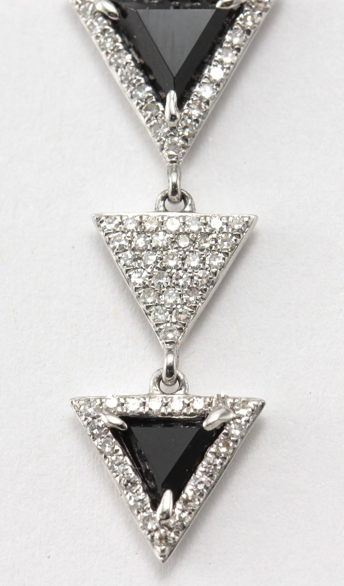 An Elegant Modern pair of Diamond and Black Onyx Dangling Triangles Earrings crafted from Solid 14 Karat White Gold. These earrings feature Triangular Black Onyx Links that are set with Diamonds along with an additional pave' Triangle dangling  2