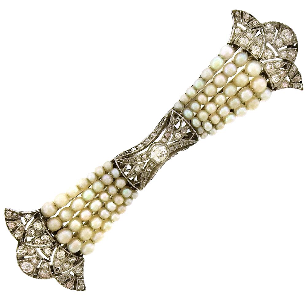 Exquisite Edwardian era bar pin, circa 1910, made in France, is a perfectly proportioned tapered brooch, its diamond-set platinum finials in an acanthus leaf motif, with four tapering lines of natural pearls, and diamond center.  The brooch measures