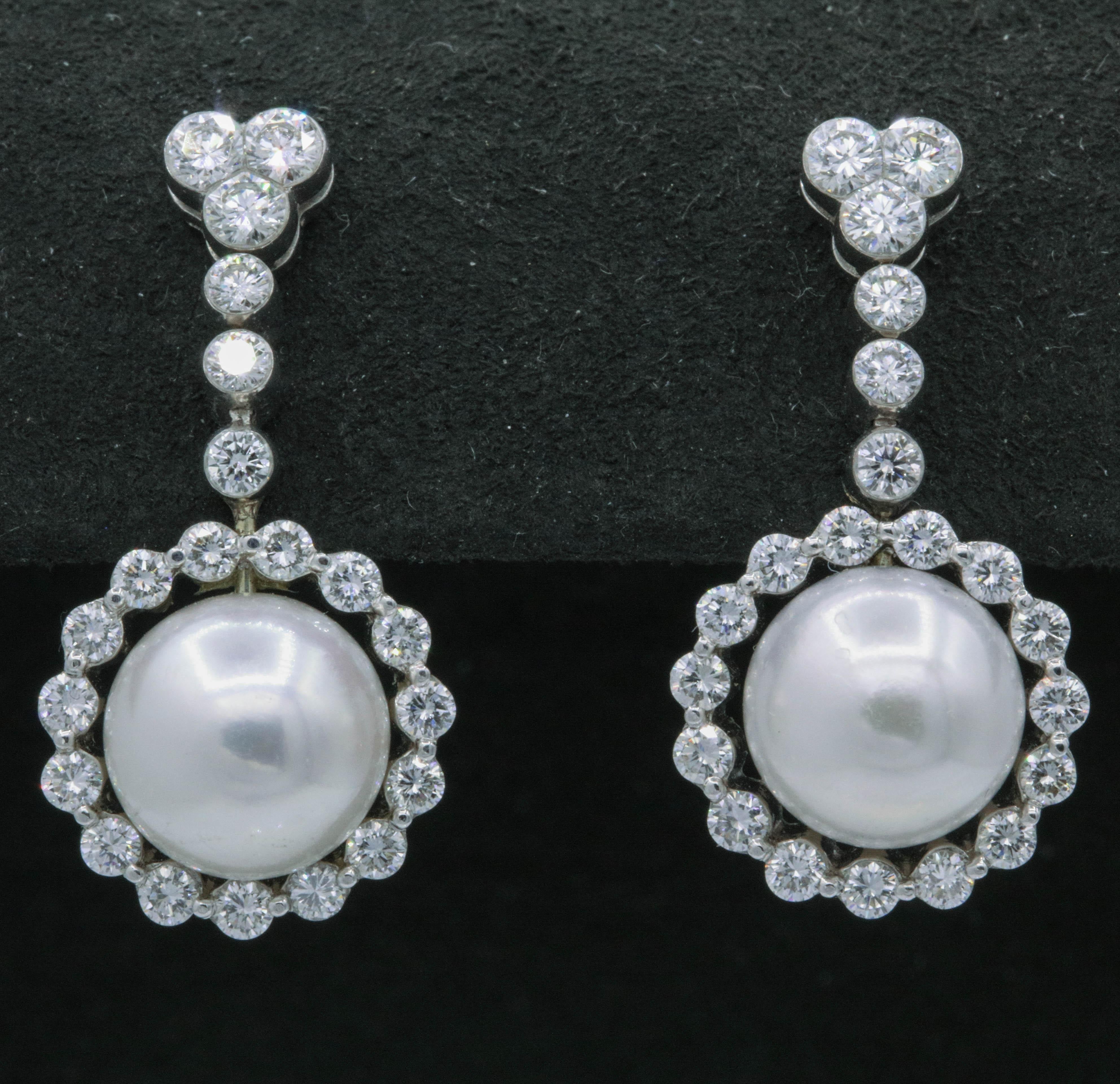 These elegant earrings features two pearls, 9.5 mm, surrounded by 42 round brilliants weighing 1.55 carats, in 18k white gold.  
Color: G-H
Clarity: SI