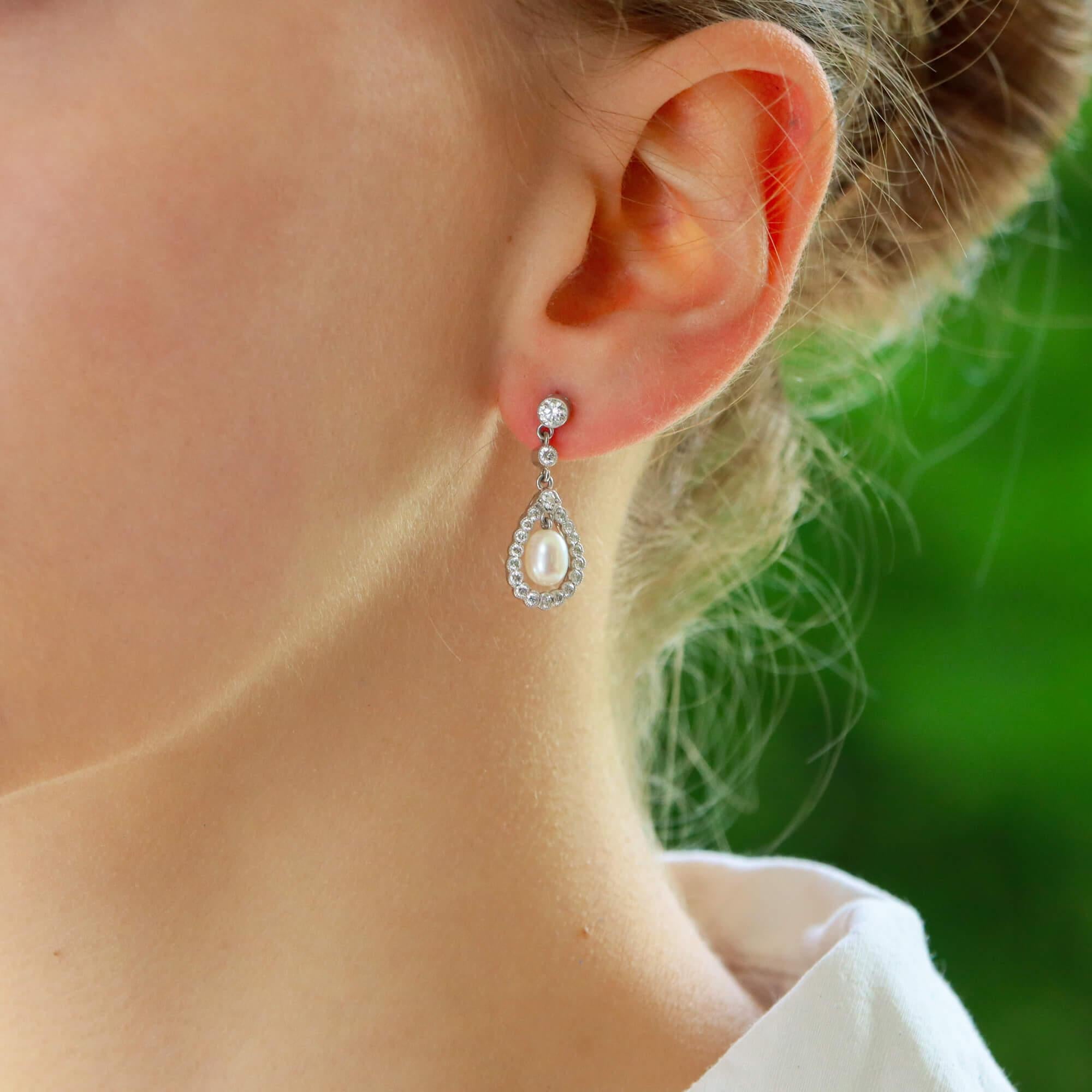 A beautiful pair of diamond and pearl garland drop earrings set in 18k white gold.

Each earring prominently features a 5 x 7-millimetre pearl that elegantly hangs within a circular diamond set garland motif. To the top of the pearl is a single