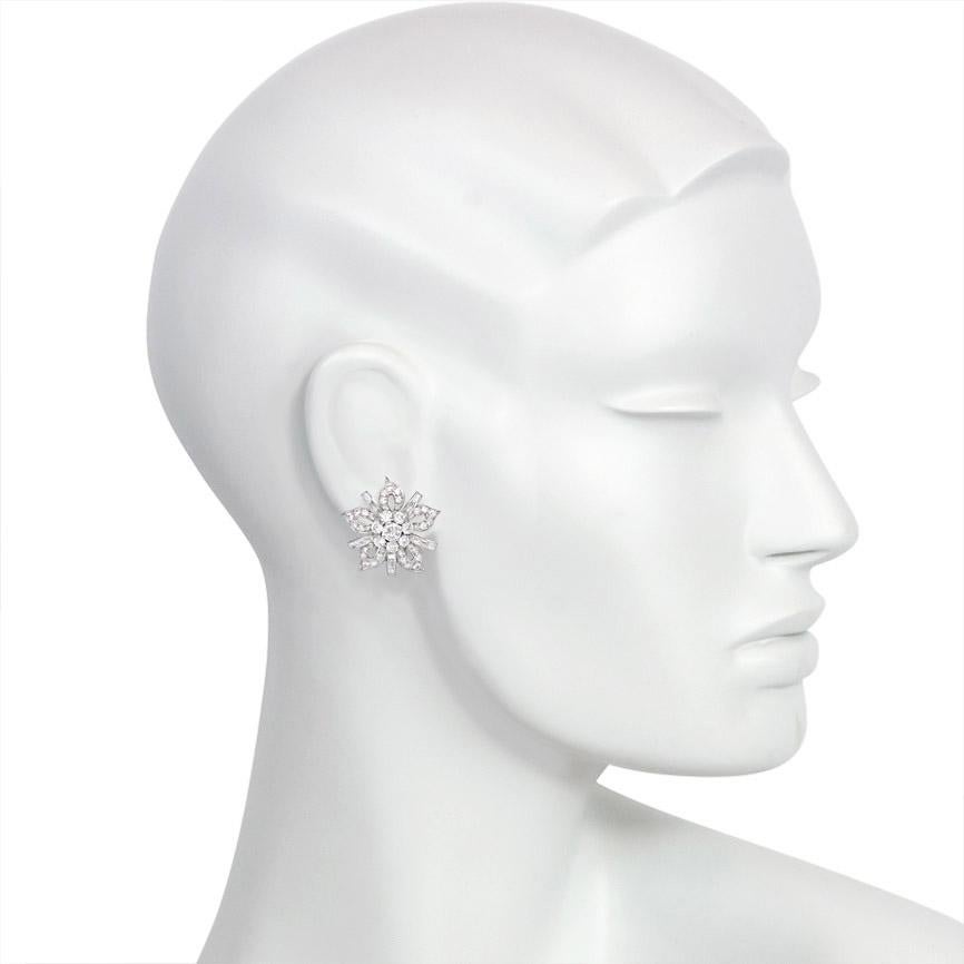 A pair of diamond clip earrings of open flower head design with round and baguette stones, in platinum. A beautiful choice for a bride to wear on her wedding day!  Atw 6.36 cts. diamonds
