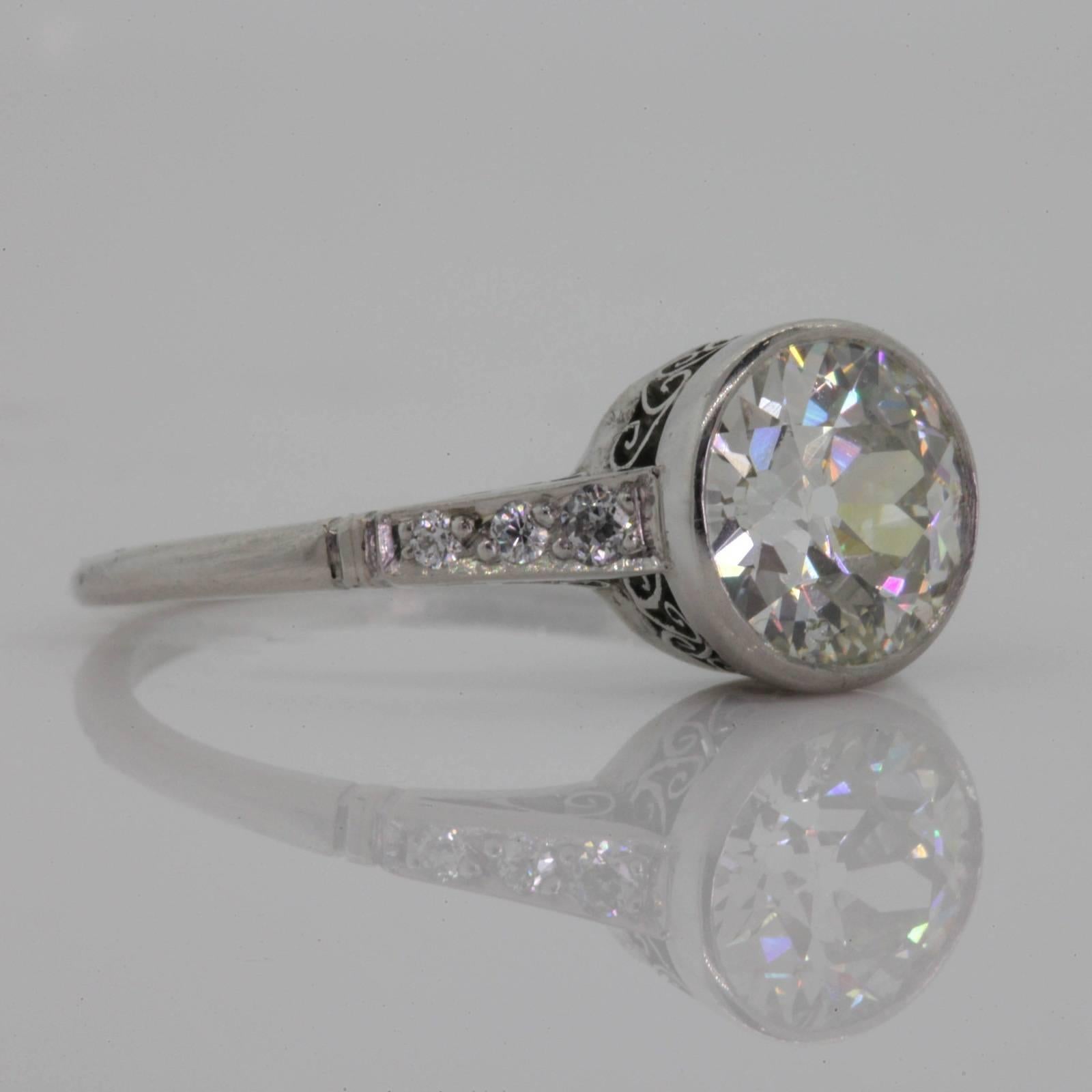 A lovely replica of a 1920's diamond and platinum ring, this handmade beauty showcases a 1.60 carat Old European cut Diamond K color - SI1 clarity.  The diamond is bezel set in a filigree basket, the ring  with graduating shoulders set with six Old