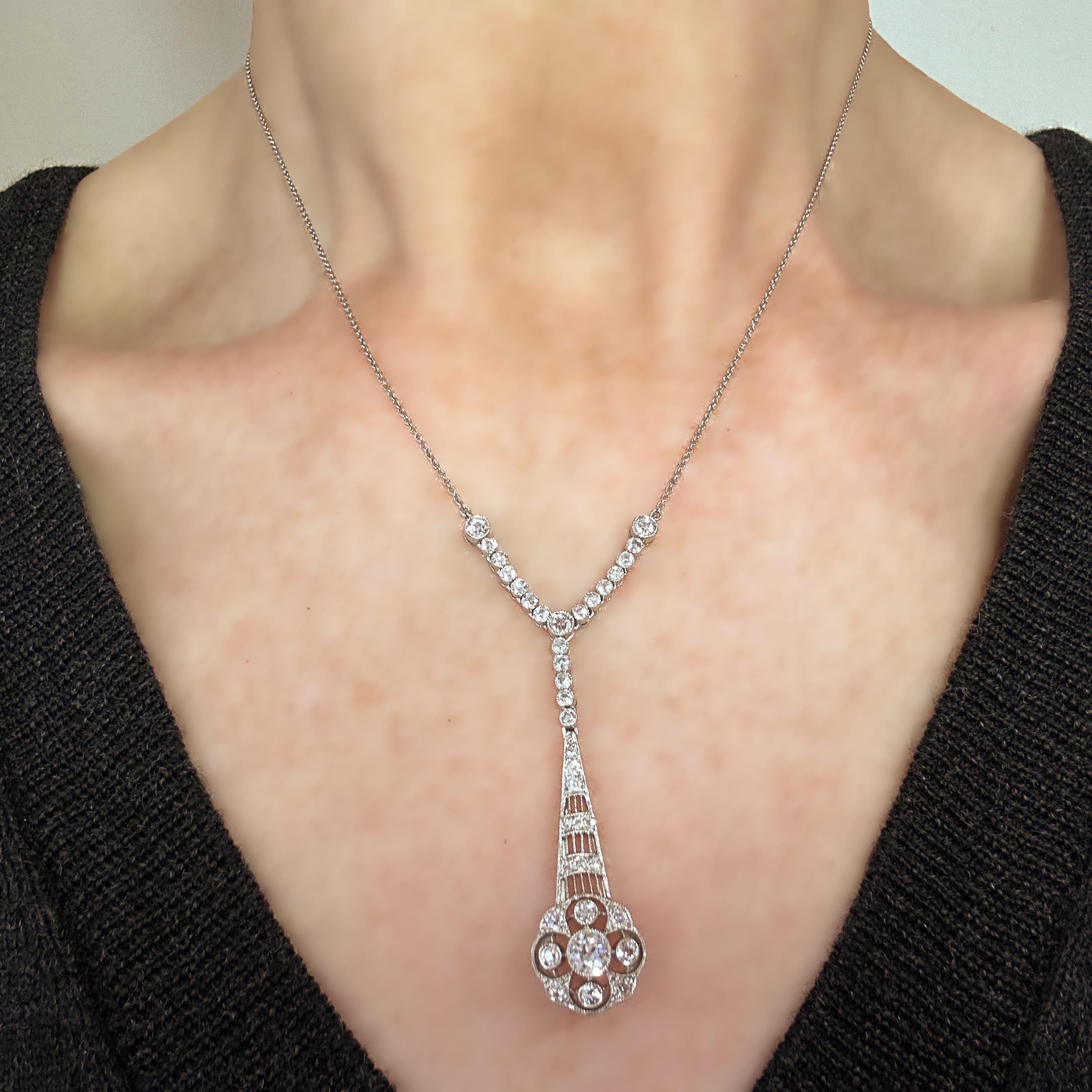 An Edwardian style diamond pendant, old-cut diamonds set in an openwork floral cluster drop, suspended from a row of collet set diamonds, mounted in platinum, on an integrated trace chain, length of drop 35mm. Estimated total diamond weight