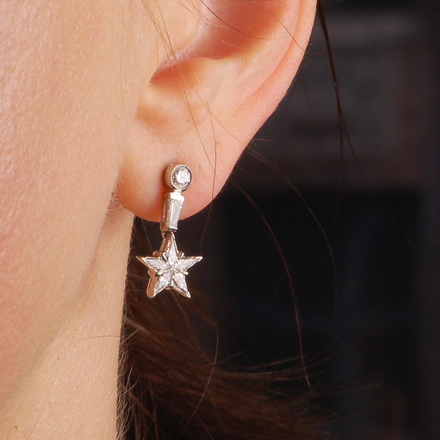These brilliant little star earrings features a very thoughtful layout of different diamond cuts.  Each star is comprised of five sheild cut diamonds and dangles from a bar set tapered baguette diamond. A bezel set round diamond is the top of the