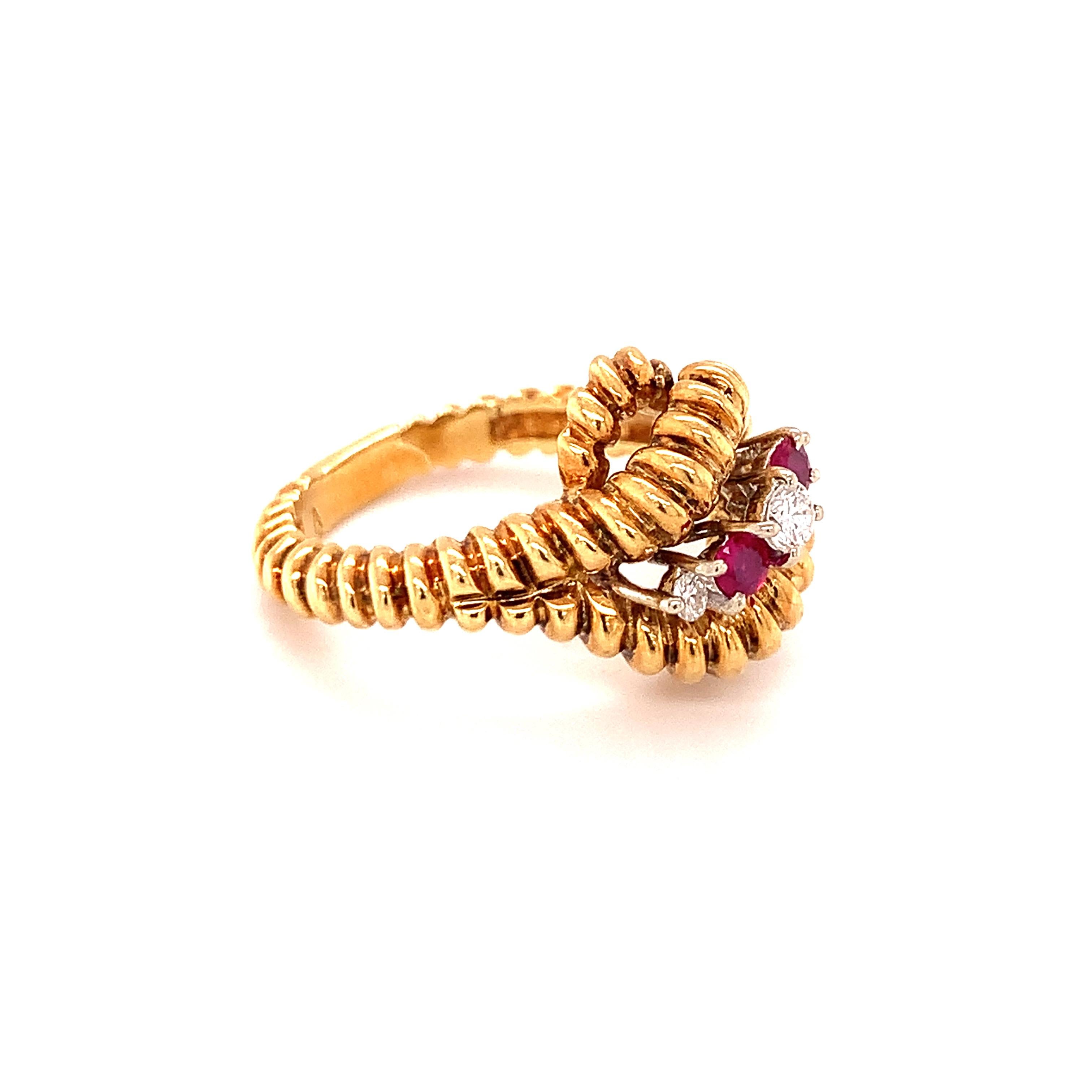 Diamond and ruby 18K yellow gold ring featuring three round brilliant cut diamonds totaling 0.20 ct. with H color and SI-1 clarity and two round brilliant cut rubies totaling 0.18 ct. The ring features a puffed, ribbed gold design throughout the