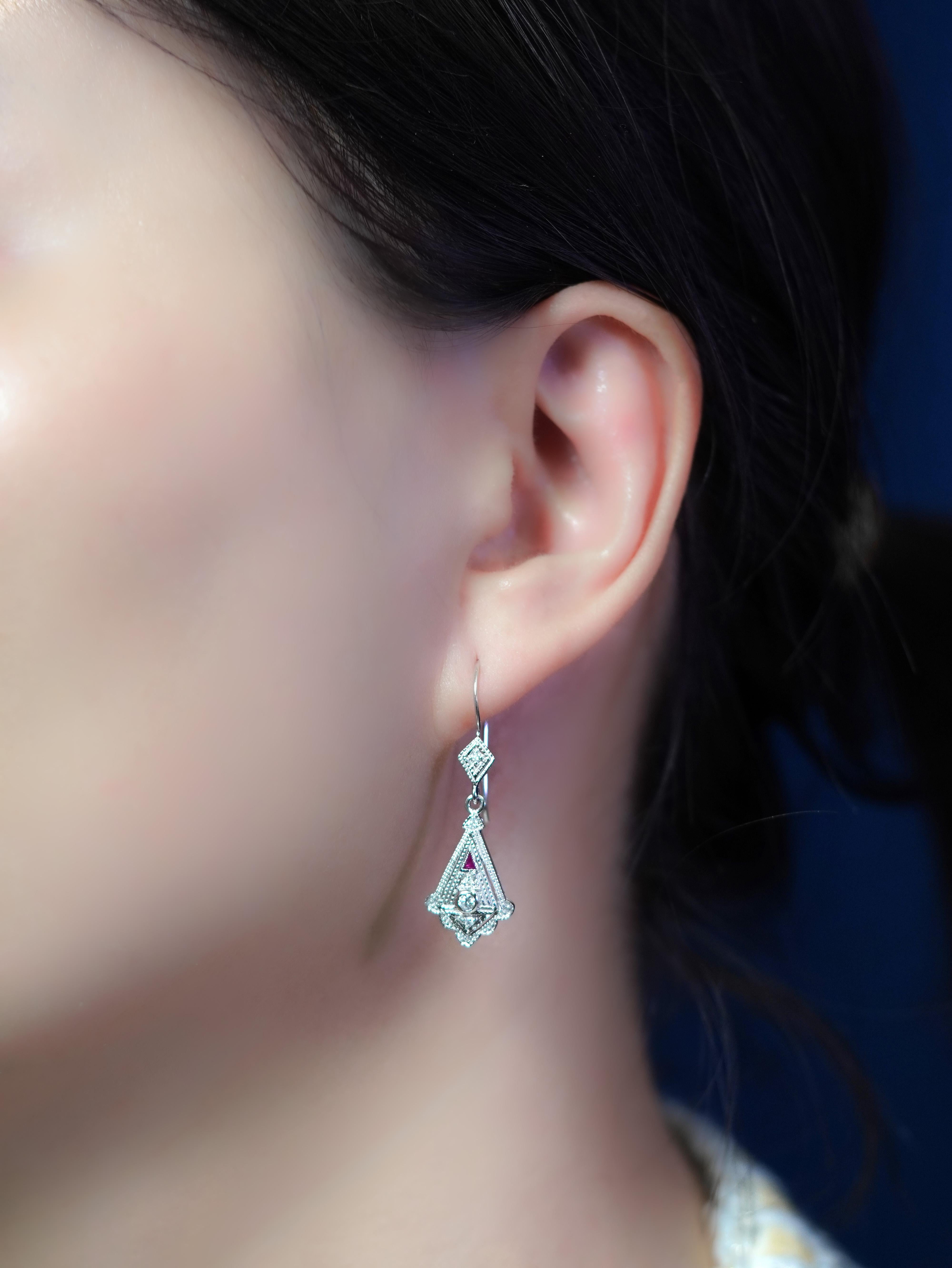 A brilliant round diamond gleams at the center, crowned by a striking triangle-cut ruby that adds a fiery touch of vintage drama. The contrast of crisp diamond light and rich ruby red creates a look that’s both elegant and unforgettable. Inspired by