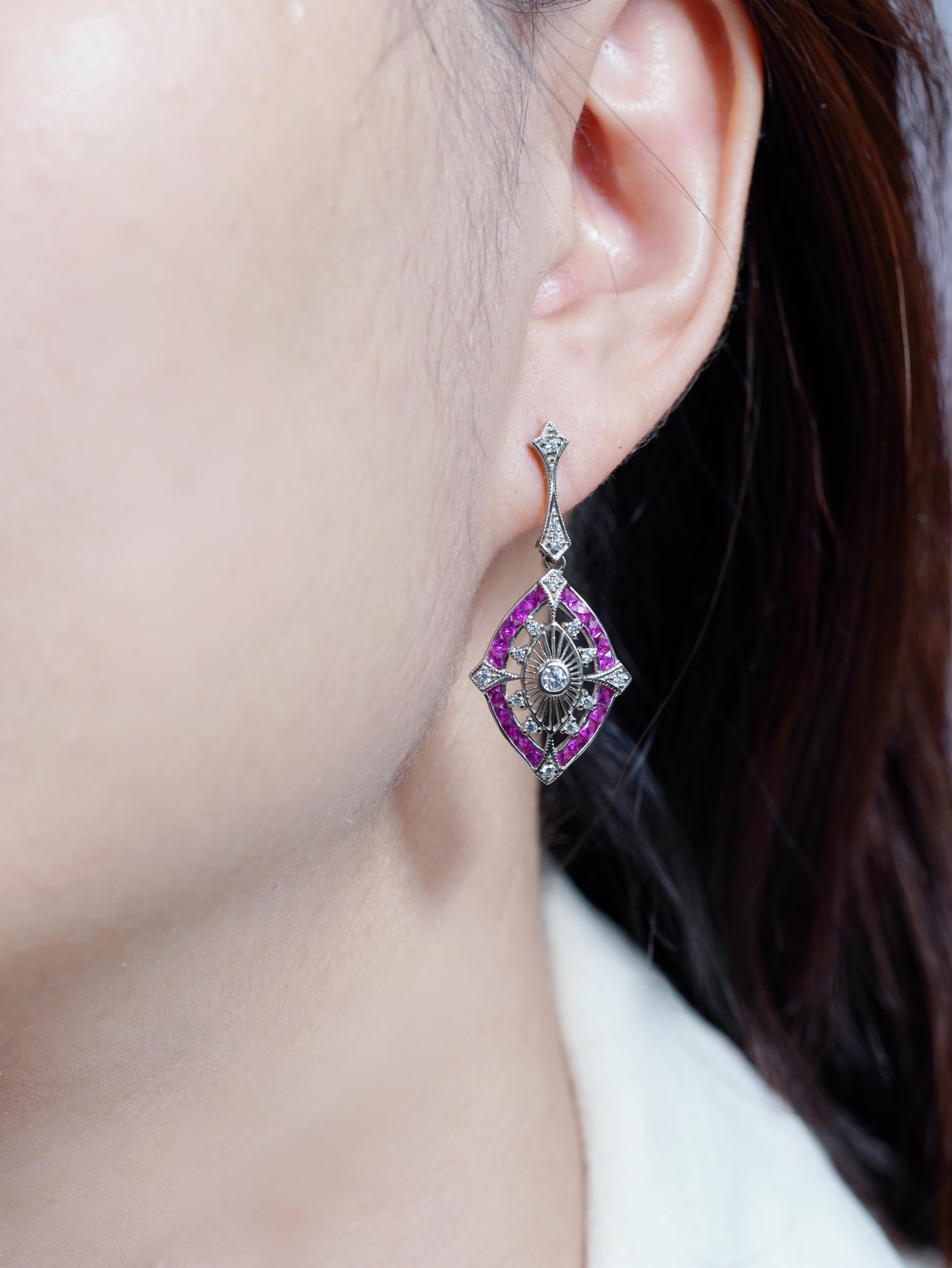 A refined expression of Art Deco elegance, this pair of drop earrings showcase a brilliant diamond at the center of a striking marquise silhouette. Surrounding the centerpiece is a vivid frame of French-cut rubies, arranged to highlight the