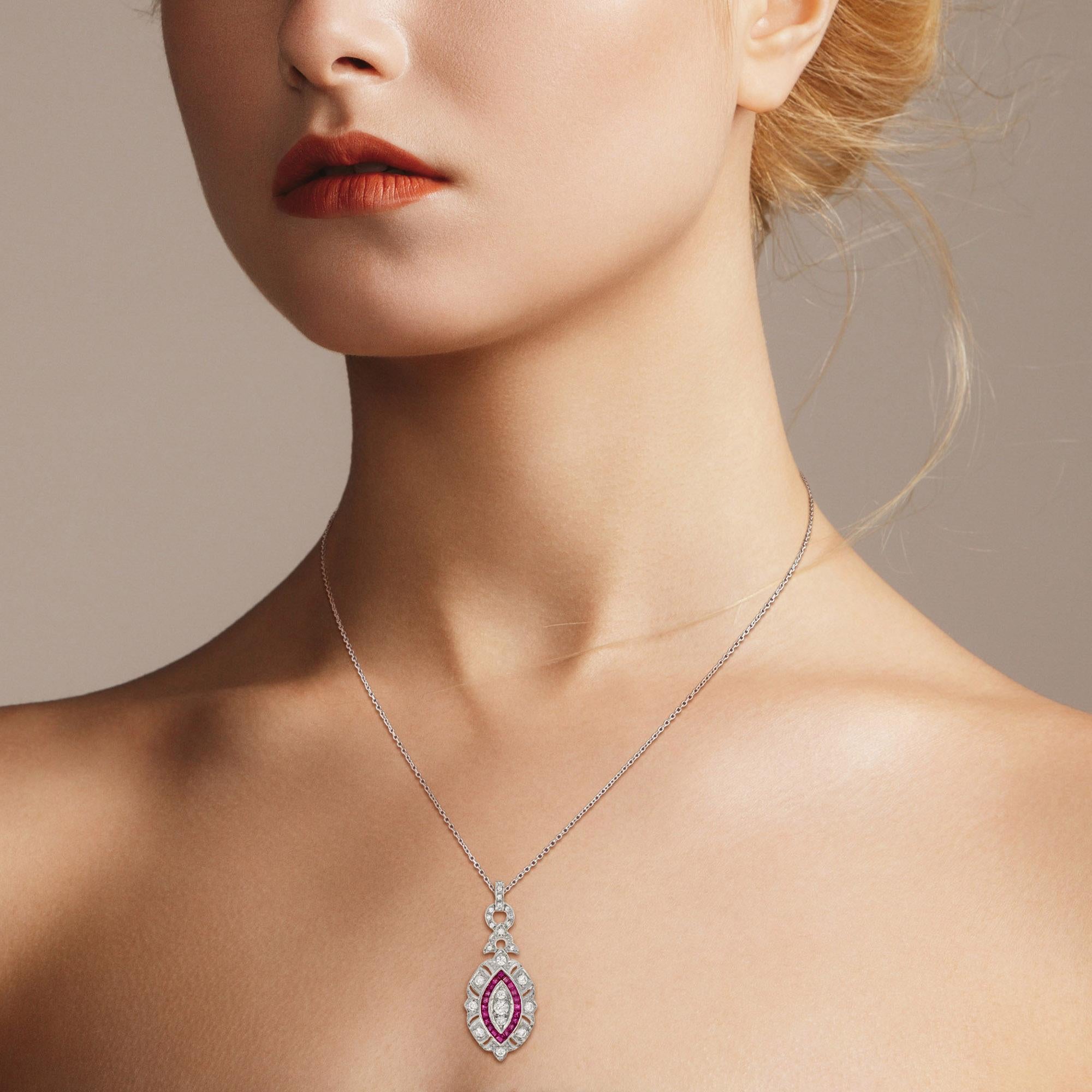 This beautiful Art Deco style pendant is finished in brightly polished 18K White gold. Delicately set across the face of the pendant are three round diamonds surrounded by French cut natural ruby. The entire pendant is adorned with round diamonds. A