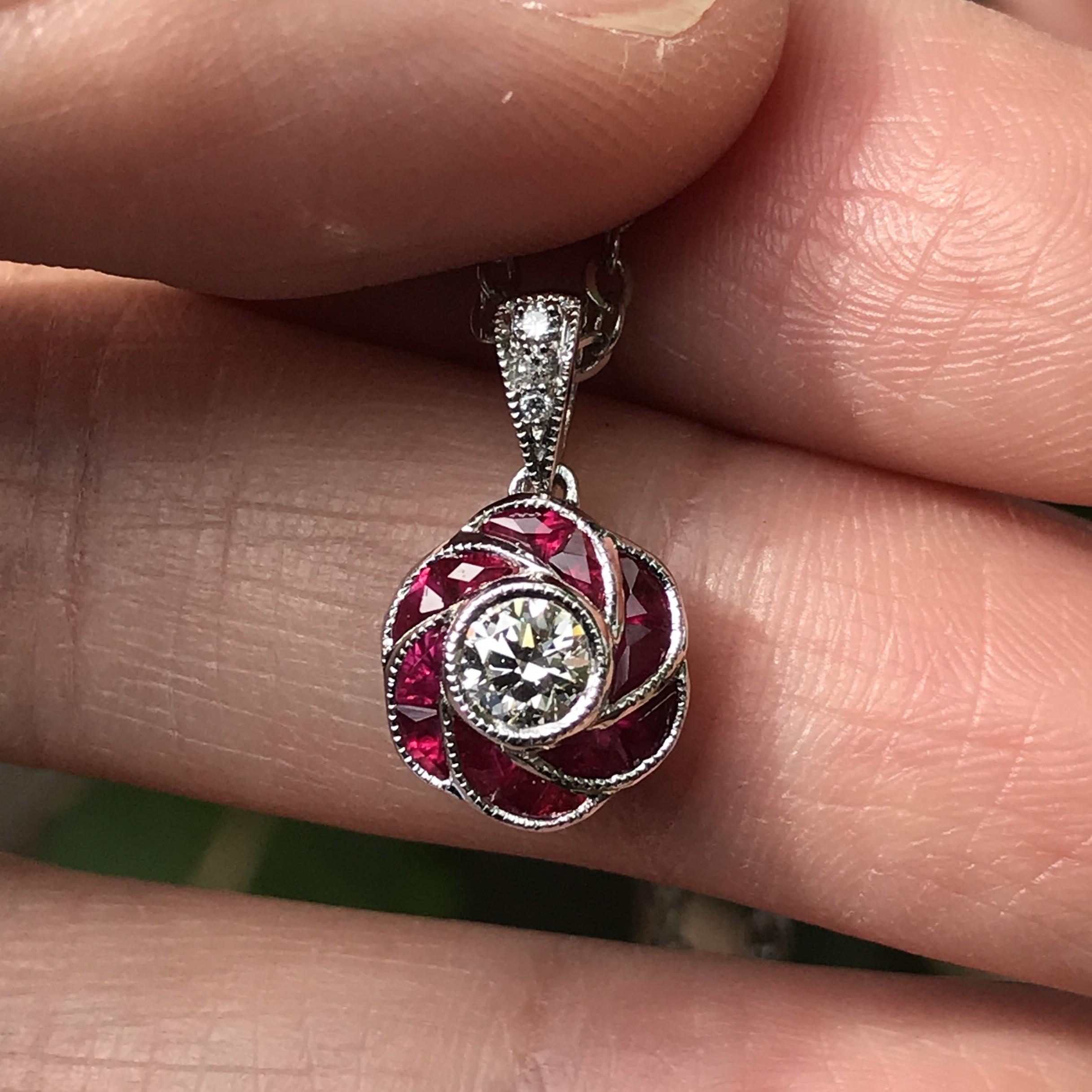 Questo ciondolo a forma di rosa rossa con diamanti e rubini in stile Art Déco presenta un diamante scintillante al centro, che rappresenta il delicato stame della rosa, mentre i ricchi rubini rossi formano gli splendidi petali. Il design cattura