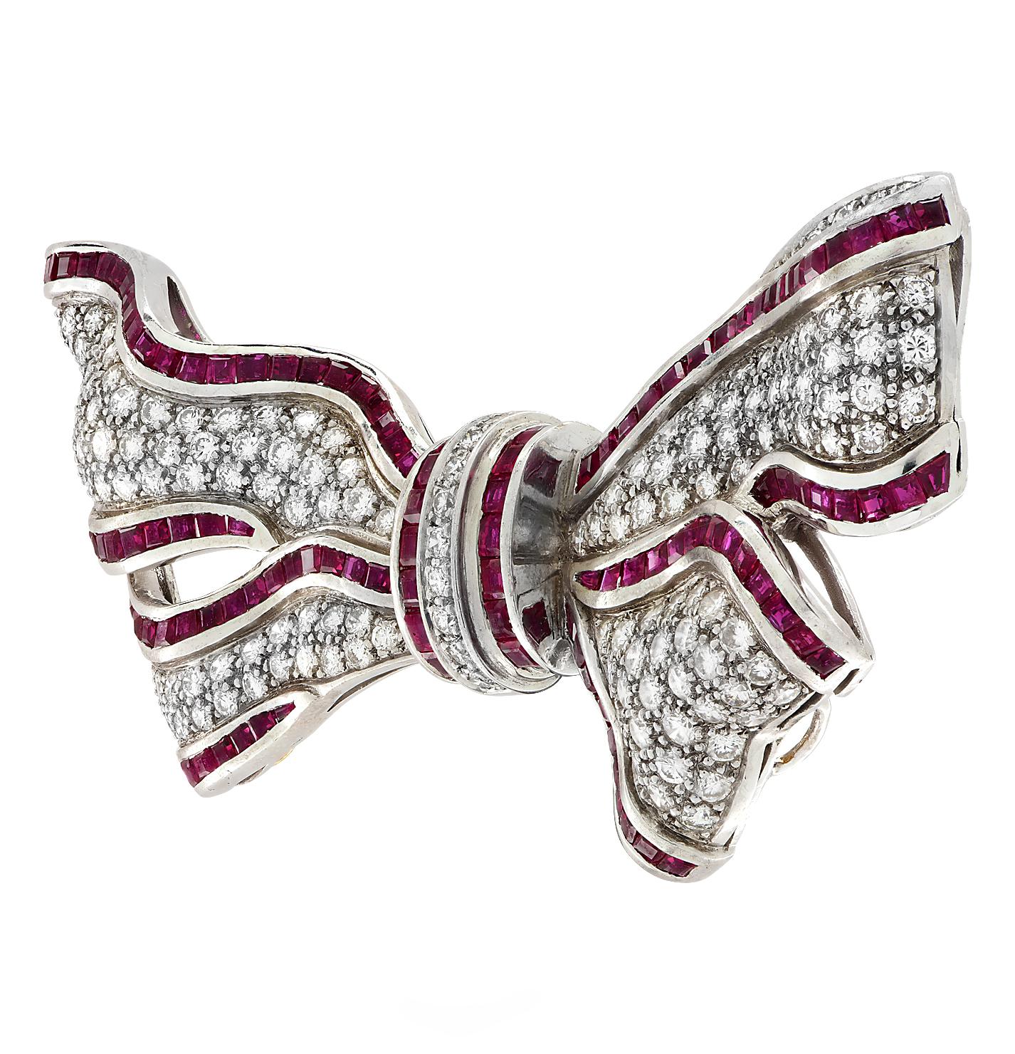 Delightful brooch pin crafted in 18 karat white gold featuring round brilliant cut diamonds weighing approximately 5.33 carats total G color VS clarity, trimmed with 105 square cut rubies weighing approximately 4 carats total, fashioned into a bow.