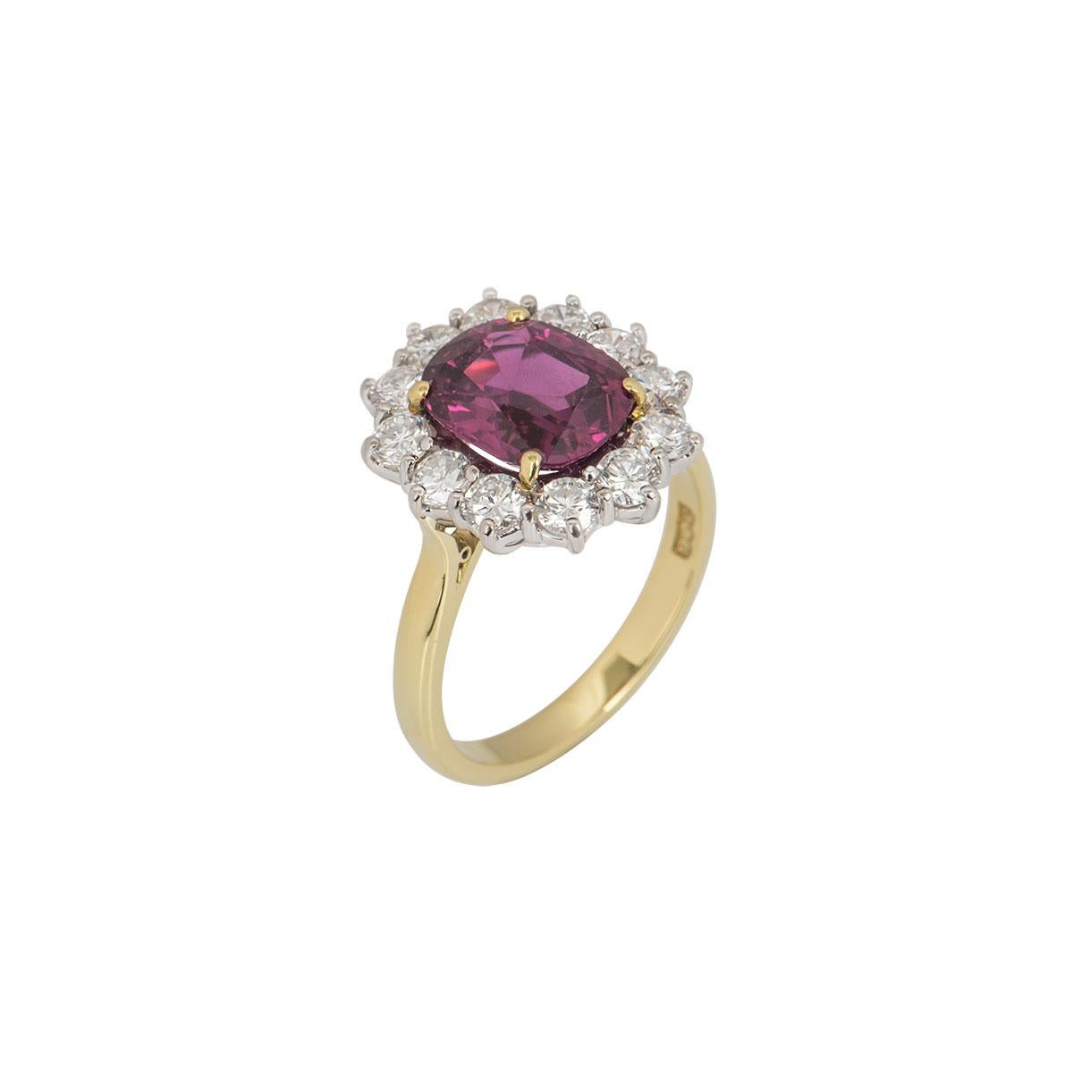 A beautiful 18k yellow gold diamond and ruby cluster ring. The ring is set to the centre with a ruby in a four claw setting dispersing a rich red hue throughout with the Origin as Thailand. Accentuating the central stone are 12 round brilliant cut