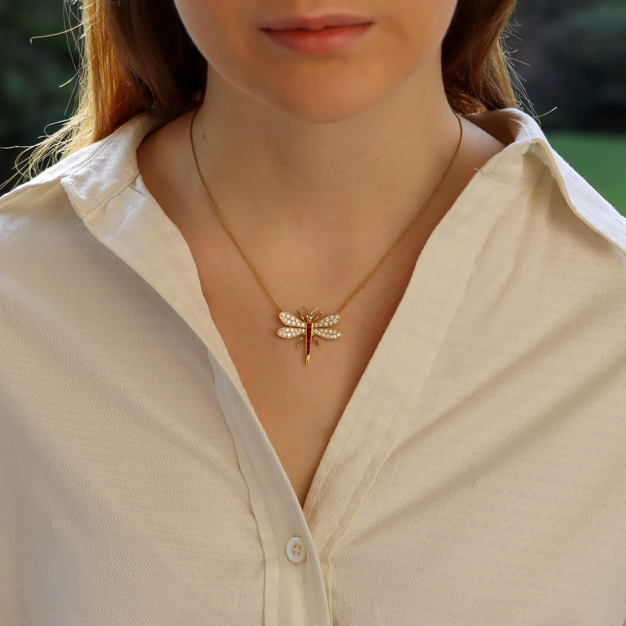 A beautiful ruby and diamond dragonfly pendant necklace set in 18k yellow gold.

This rather unique piece depicts a naturalistic dragonfly fixed on a simple, yet secure, yellow gold trace chain. Firstly, the body of the insect is composed of