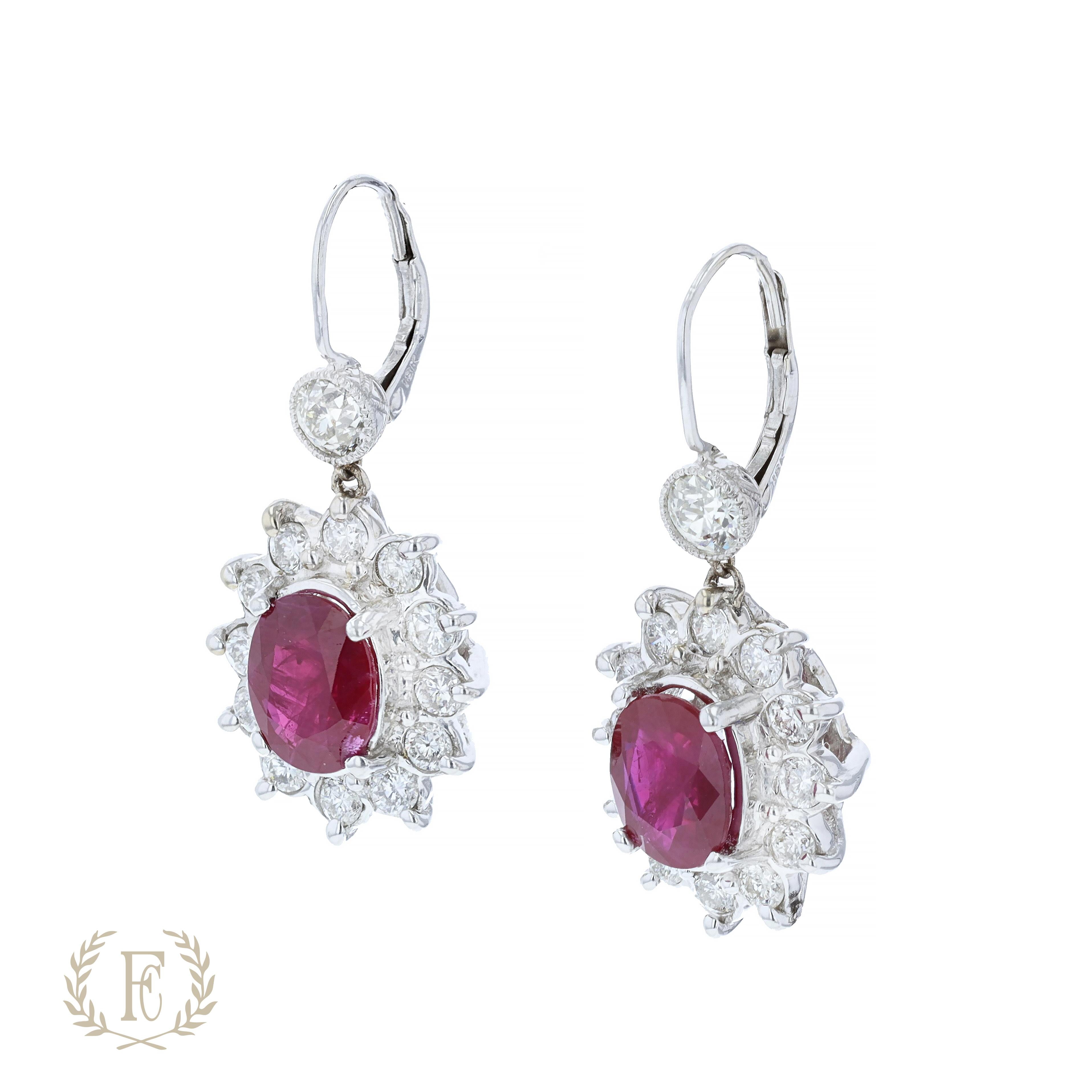 One pair of 18 k white gold and ruby diamond dangle earrings containing 2 oval shaped rubies that weigh 6.20 ctw. The earrings also contain 2 old mine diamonds that weight .75 ctw and 24 round diamonds weighing 3.20 ctw.