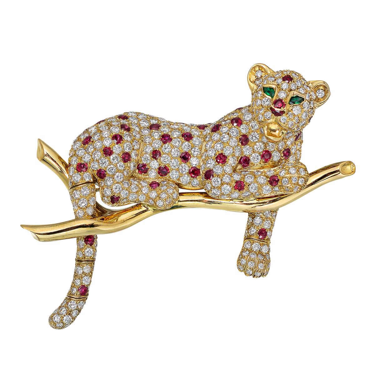 Vintage diamond, ruby and gold brooch, designed as a leopard lying atop a branch adorned with pavé-set fine colorless round-cut diamonds and round faceted ruby 'spots', as well as pear-shaped emerald eyes, mounted in 18k yellow gold, the leopard's