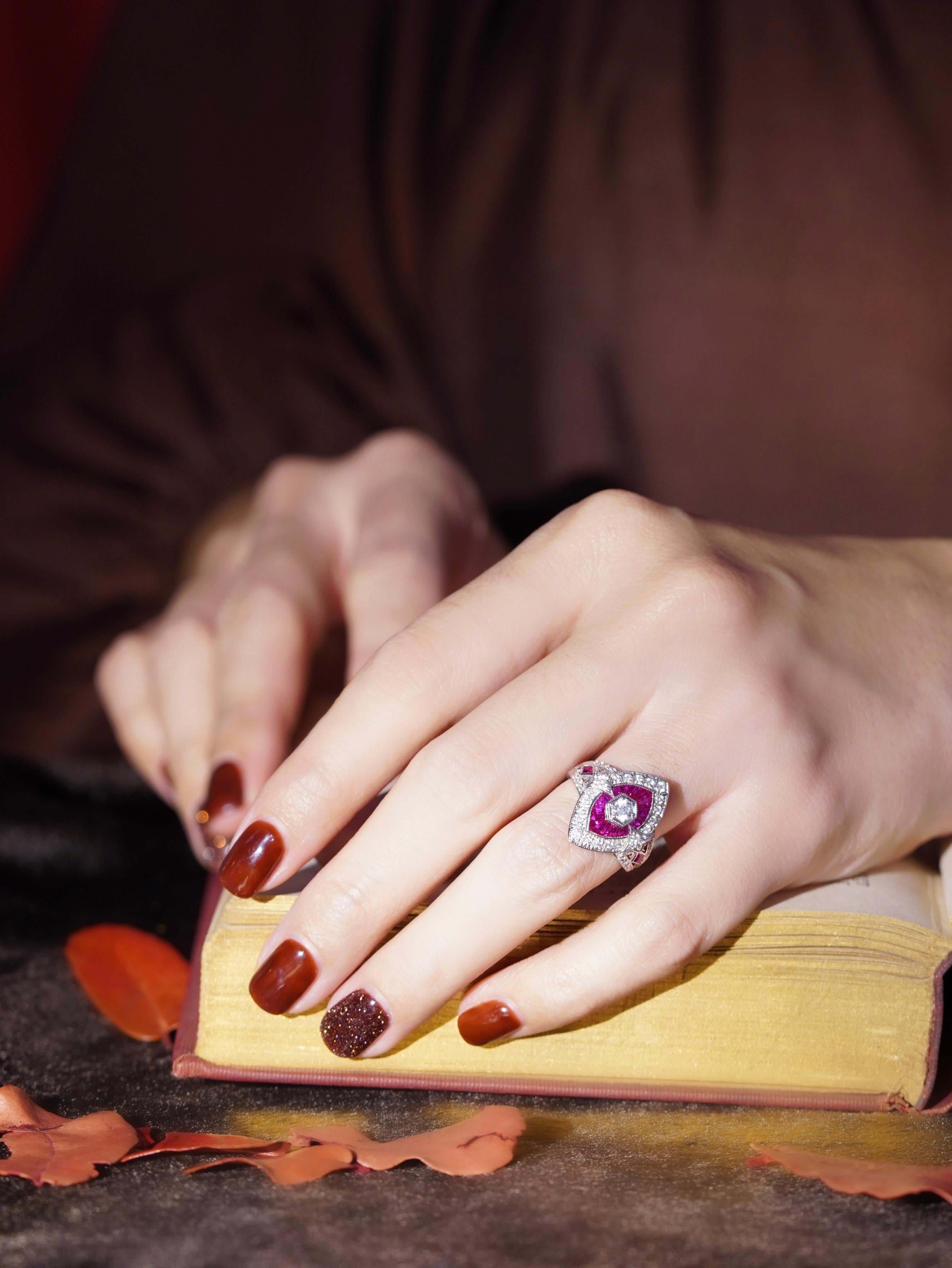 Fai una dichiarazione abbagliante con questo anello in stile Art Deco con diamanti e rubini a forma di marquise. Un diamante brillante è al centro della scena, circondato da una vibrante aureola di rubini taglio francese. La cornice esterna di
