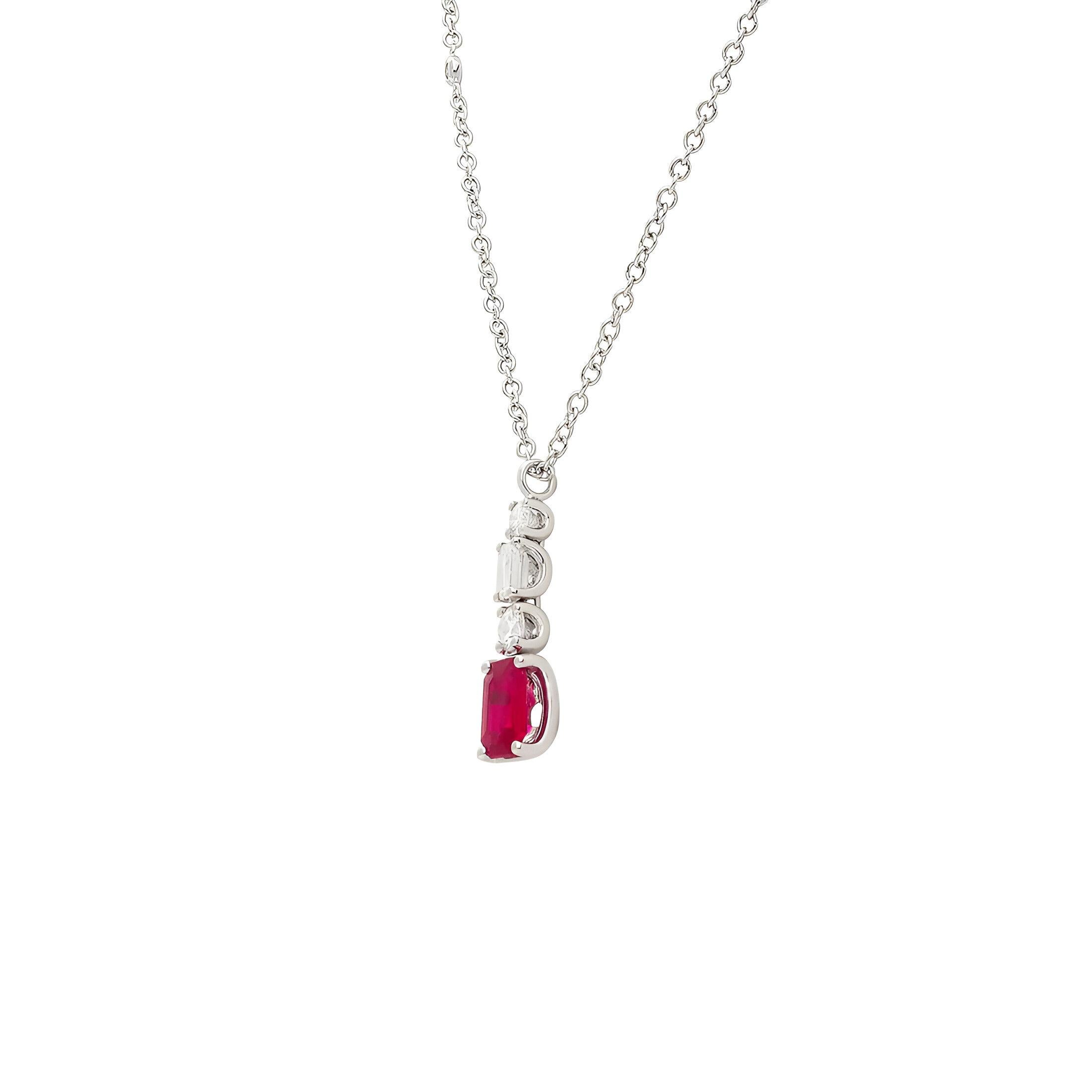 Ce collier exceptionnel, forgé en or blanc 18kt, pèse 3,90 grammes et est suspendu à une chaîne de 45 cm avec un œillet à 42 cm pour un port polyvalent. Le design est centré sur un rubis captivant de 0,91 carat taillé en émeraude, une pierre révérée