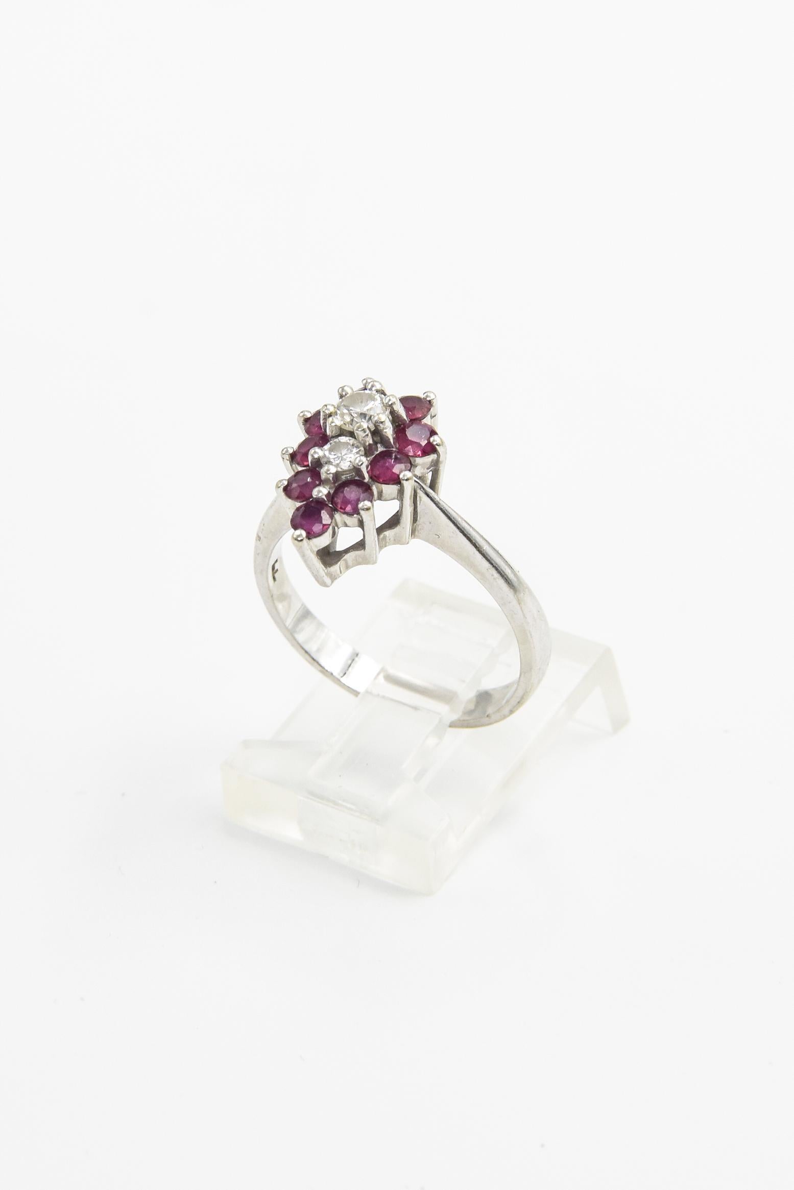 Lovely 14k white gold ruby and diamond cluster ring featuring .15 carat and .07 carat approximate weight diamond centrally set between between 9 prong set rubies.  Marked 14k.
US size 6.5.