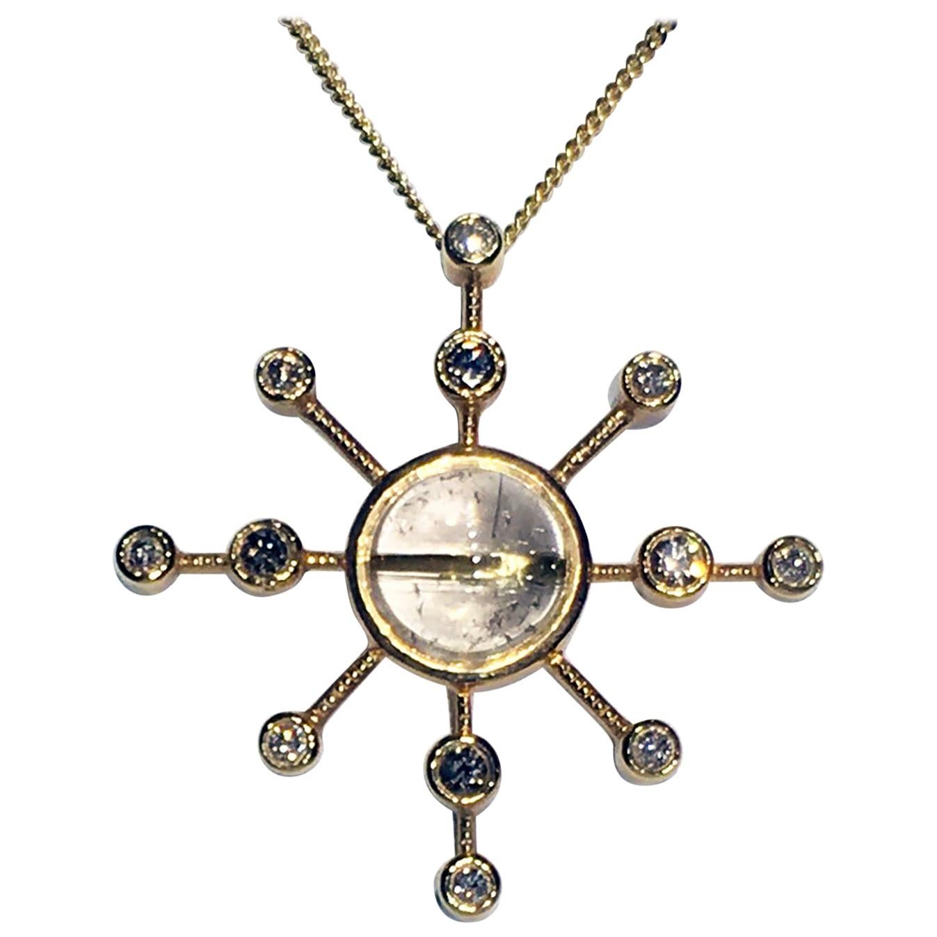 An 18k Yellow Gold Diamond Starburst Pendant set with Rutillated Quartz. This 18kt Gold Starburst Pendant features a central Rutile Quartz Cabochon of 5.57 Carats and is surrounded by 12 Champagne Diamonds totaling 0.76 Carats. The Gold weight of