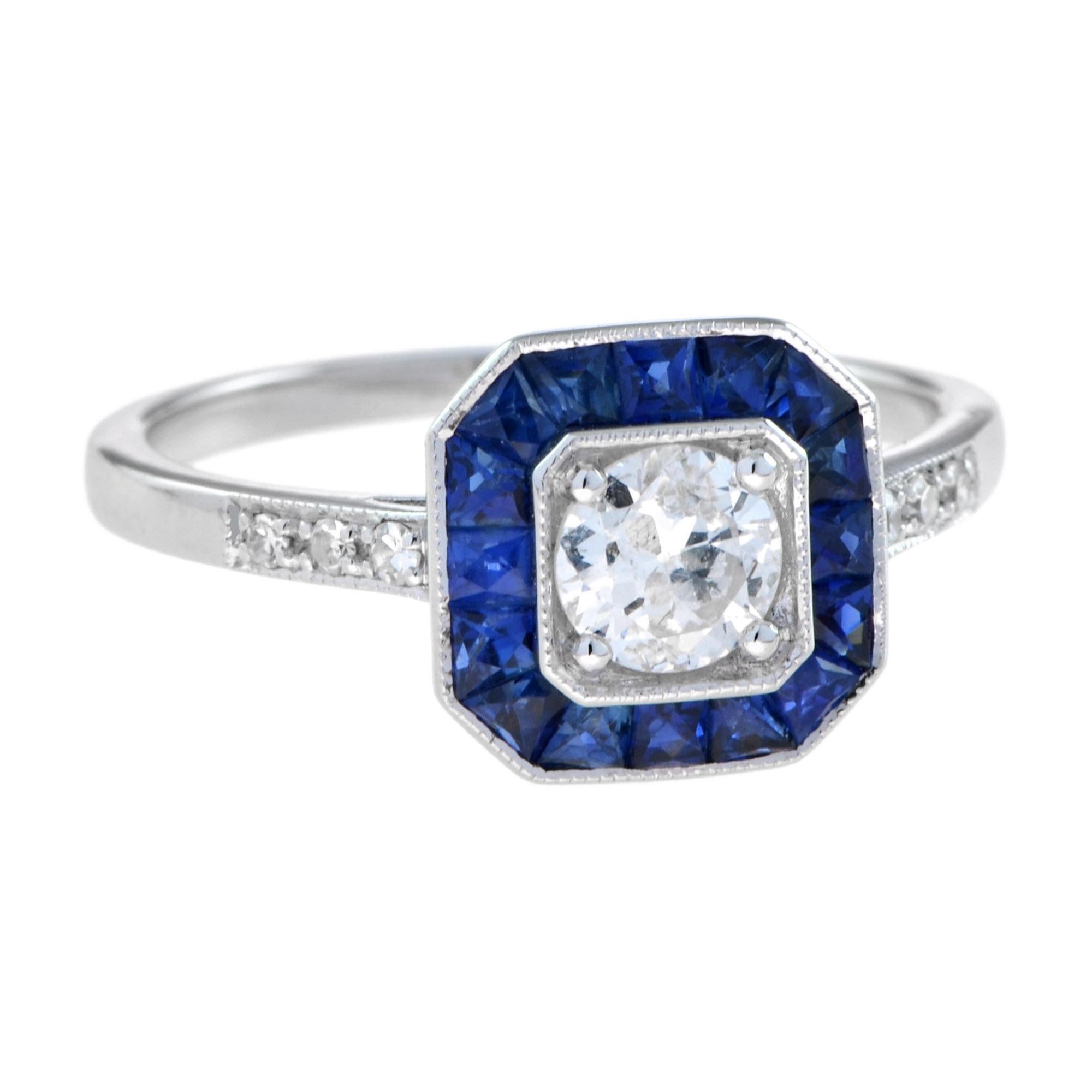 A stunning diamond and sapphire ring, centered with a beautiful round brilliant diamond setting surrounded by a fine geometric frame of French cut sapphires and with diamond set shoulders, all in a finely hand-crafted 18K white gold mount with plain