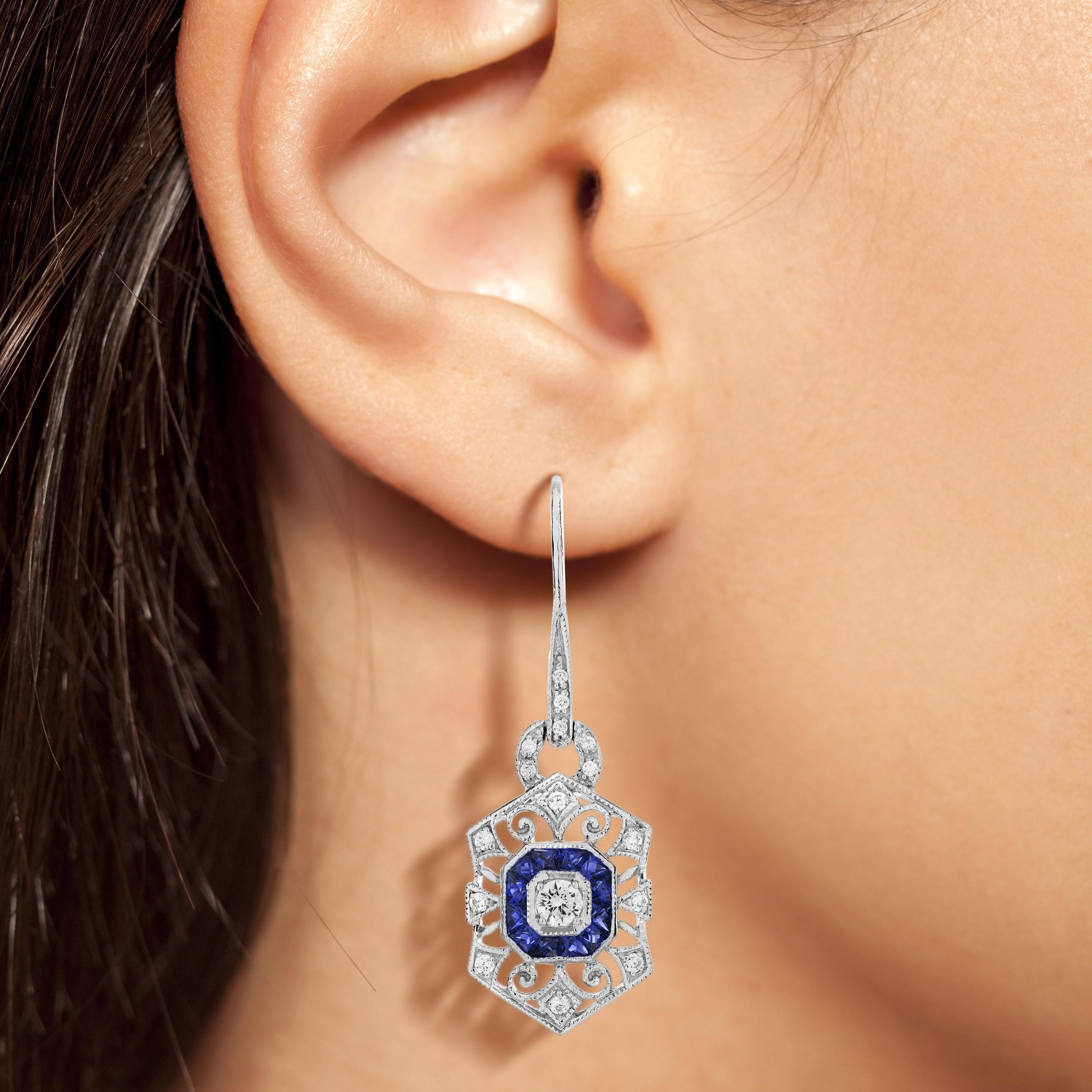 Elevate your elegance with this stunning Diamond and Sapphire Art Deco Jewelry Set. Featuring a brilliant diamond and vivid blue sapphires, the ring's sleek design exudes timeless sophistication. The matching drop earrings with geometric detailing