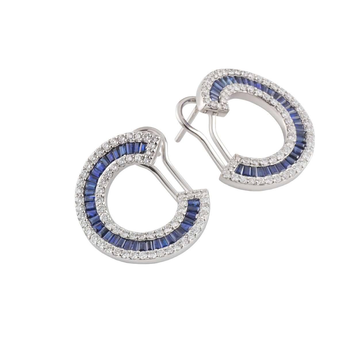 A beautiful pair of 18k white gold diamond and sapphire earrings. The earrings comprises of a spiral motif with baguette cut sapphires set through the centre with a halo of round brilliant cut diamonds. The diamonds have a weight of 1.40ct, G-H