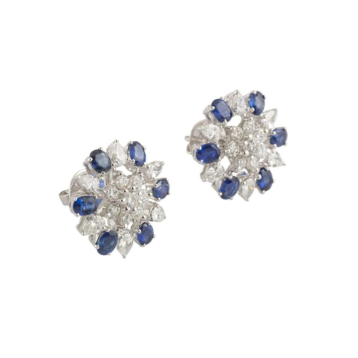 A pretty pair of 18k white gold diamond and sapphire stud earrings. The earrings comprise of a flower motif with 1 round brilliant cut diamond in the centre and 7 round brilliant cut diamonds. Complementing the flower motif are a halo of oval cut