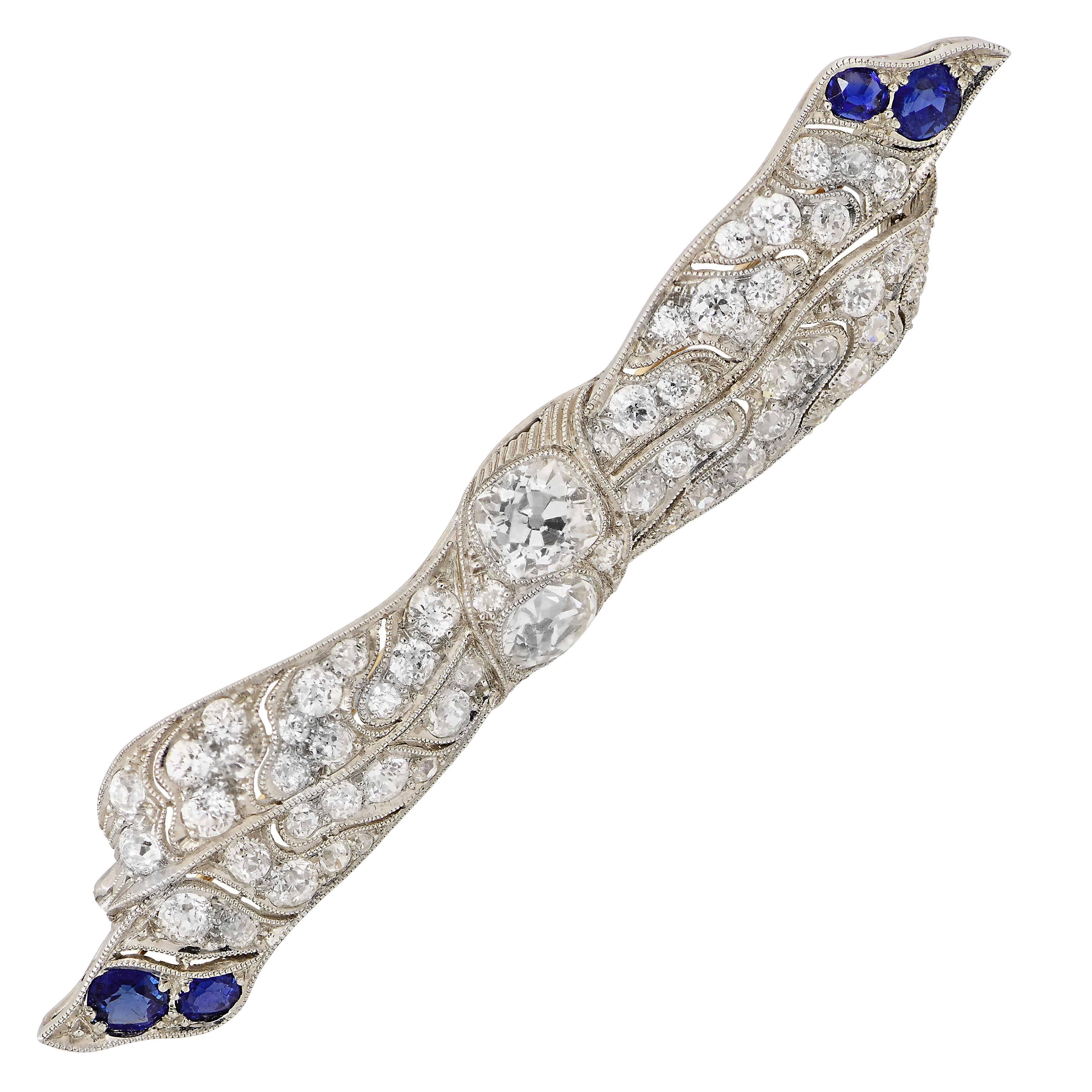 Questo bellissimo ciondolo antico Edwardian Ribbon in platino e  La spilla presenta 64 diamanti taglio old mine con un peso totale stimato di 5 carati e quattro zaffiri taglio ovale con un peso totale stimato di 1,5 carati. Il peso dei due diamanti