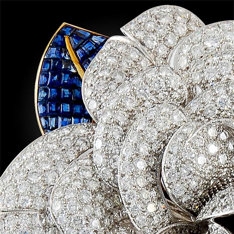 Diamond and sapphire flower brooch

Designed as a camellia blossom, petals set with brilliant-cut diamonds, mounted in platinum and 18k yellow gold.
approximately 3.50″ long and total diamond weight is approx. 25 cts.
