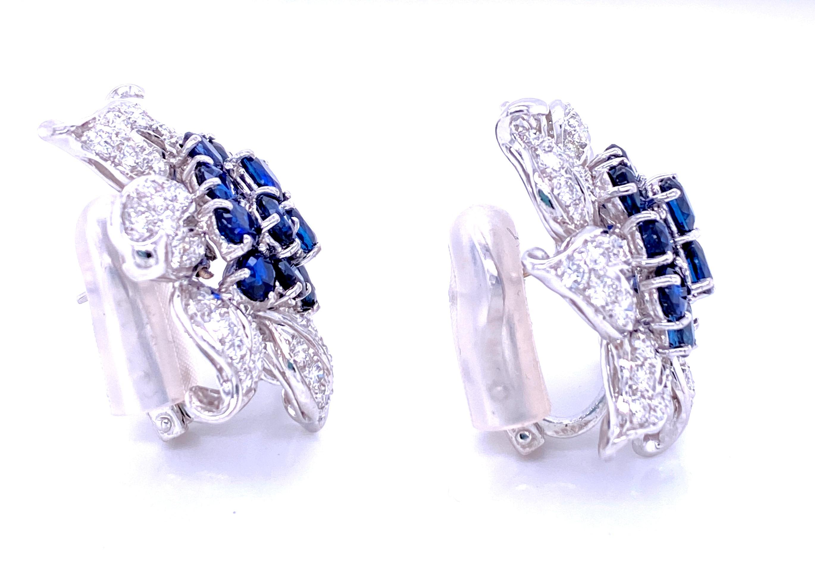 One pair of 18 karat white gold sapphire and diamond flower earrings, each prong set with twelve 4.5 x 3.5mm oval sapphires approximately 0.9 cart total weight and forty-nine round brilliant diamonds, approximately 4.50 carats total weight with