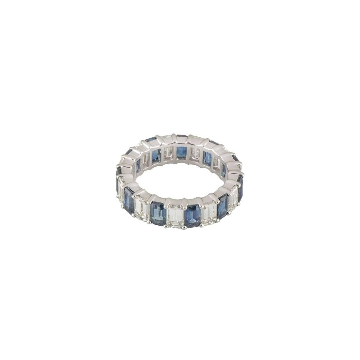 An exquisite 18k white gold diamond and sapphire full eternity ring. The ring consists of claw set baguette cut diamonds, alternating with baguette cut blue sapphires, each totalling approximately 4.40ct. The ring is a US size 6 1/2, EU size 53.5