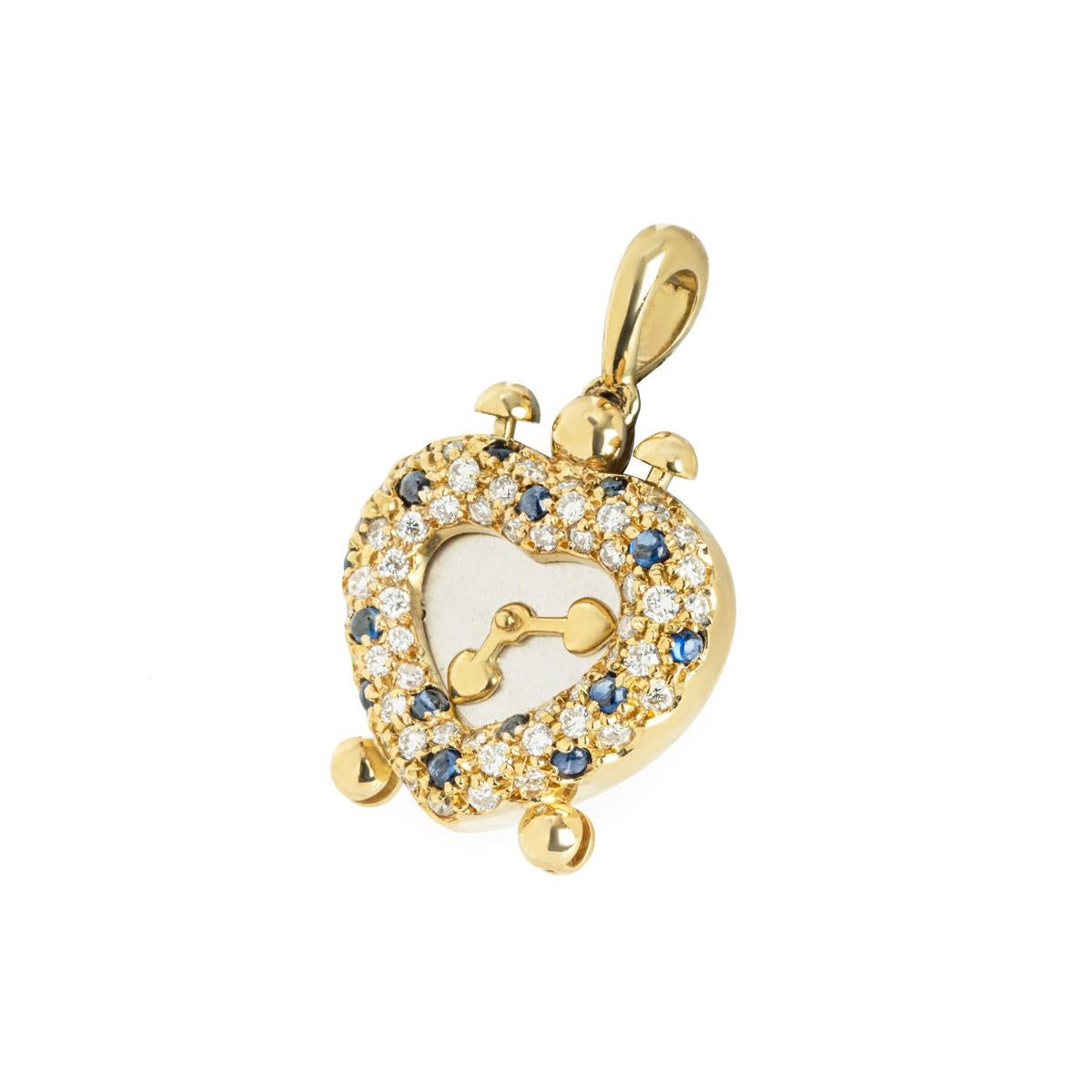 An 18k yellow gold diamond and sapphire heart clock pendant. The pendant comprises of a heart clock motif consisting of round brilliant cut diamonds and sapphires in a pave setting alternating around the outer edge with a silver centre with gold