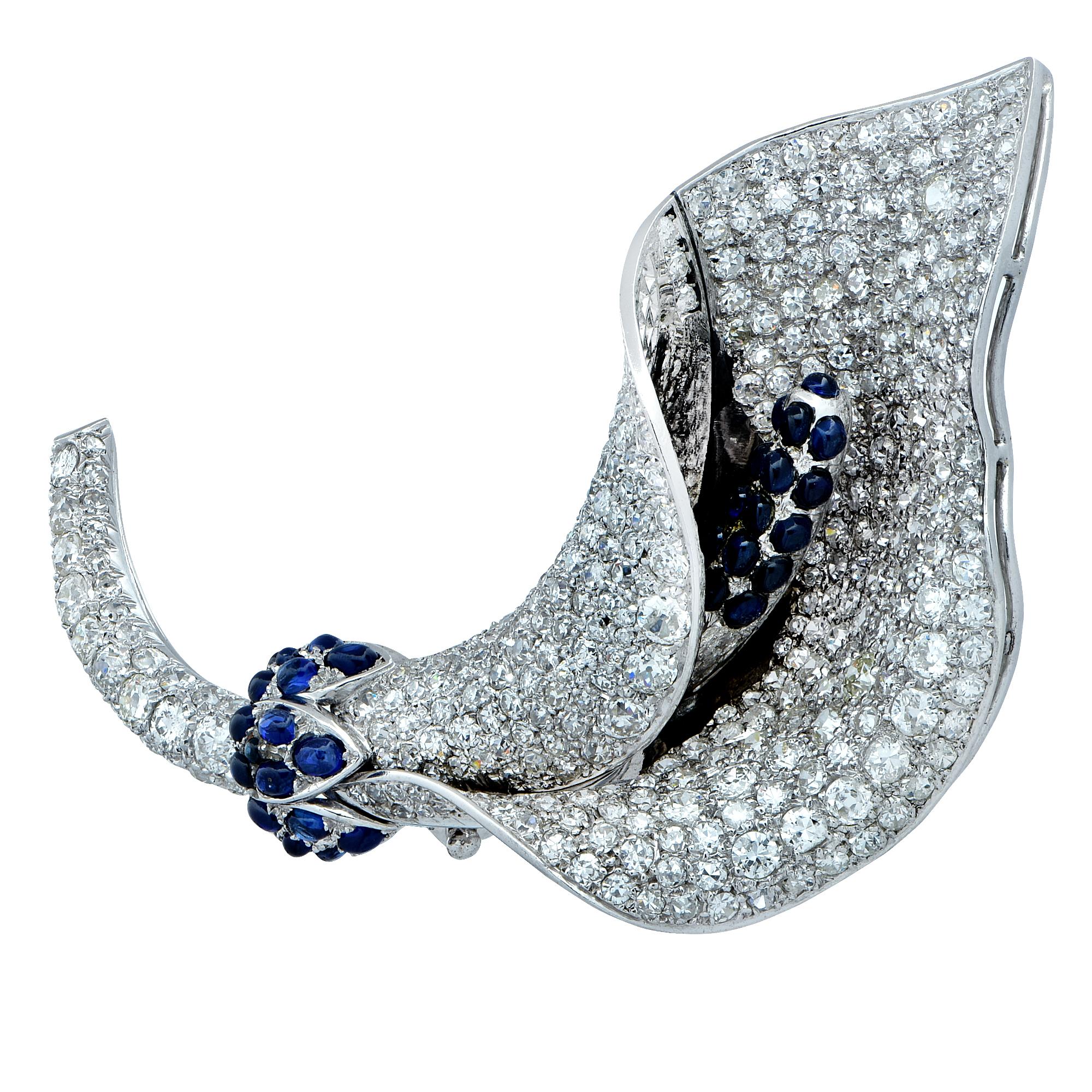 Sensational Art Deco brooch crafted in platinum, showcasing European cut and single cut diamonds weighing approximately 12 carats, G-J color, VS-SI clarity, accented by approximately 1.5cts of cabochon blue sapphires, finely crafted in a Lily. This