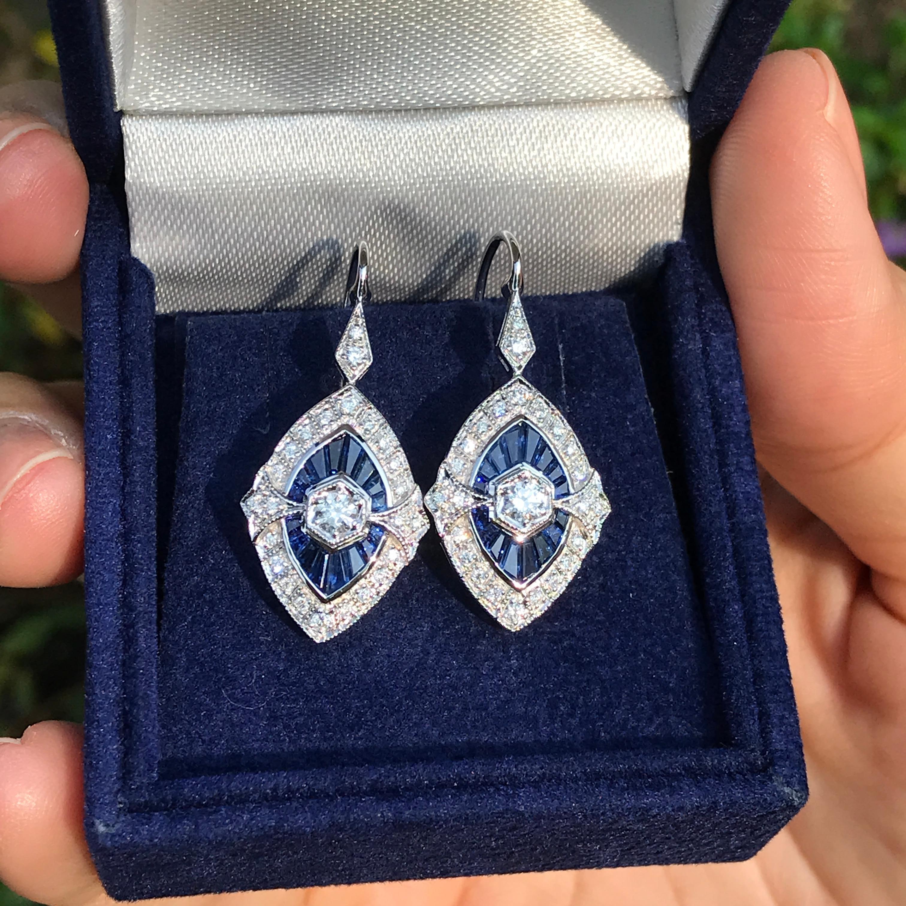 Questi orecchini a goccia con diamanti e zaffiri a forma di marquise sono caratterizzati da un diamante rotondo brillante al centro, circondato da vibranti zaffiri taglio francese e incorniciato da un diamante abbagliante. Il design è splendidamente