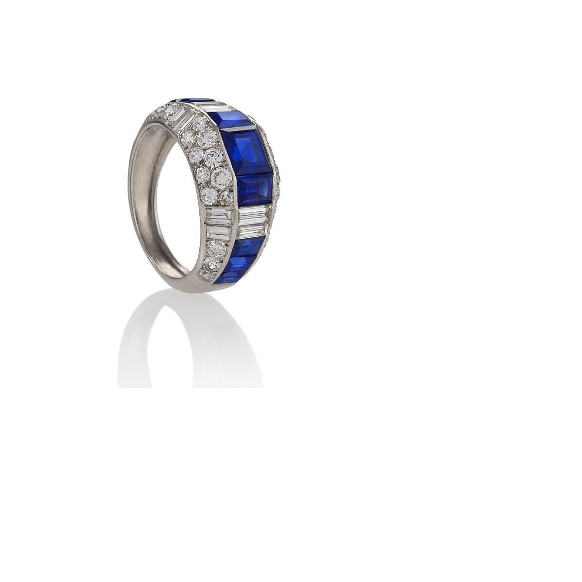 An Estate platinum ring with sapphires and diamonds. This ring centers on 9 rectangular-cut blue sapphires with an approximate total weight of 2.40 carats, 42 baguette and round brilliant cut diamonds with an approximate total weight of 3.00 carats