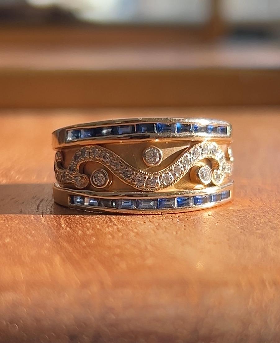 This estate 14-karat yellow gold ring showcases a sophisticated design with a striking combination of diamonds and sapphires. The band is adorned with twenty nine round brilliant diamonds measuring 1.5mm and three additional round brilliant diamonds