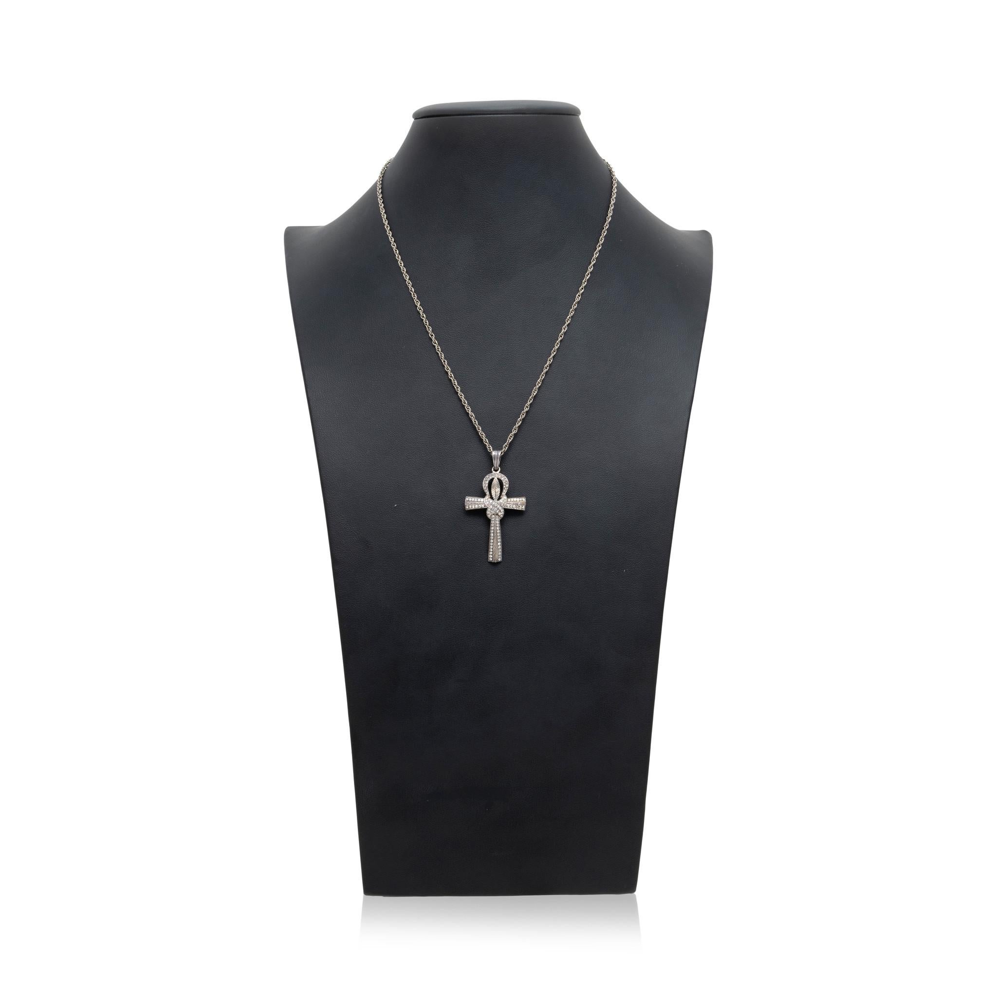 Diamond and silver cross pendant. Featuring knotted anubis style design with a total of 82 small round cut diamonds along surface weighing approximately 79cttw. Center of knot has an etched leaf design. With larger loop to accommodate more chain
