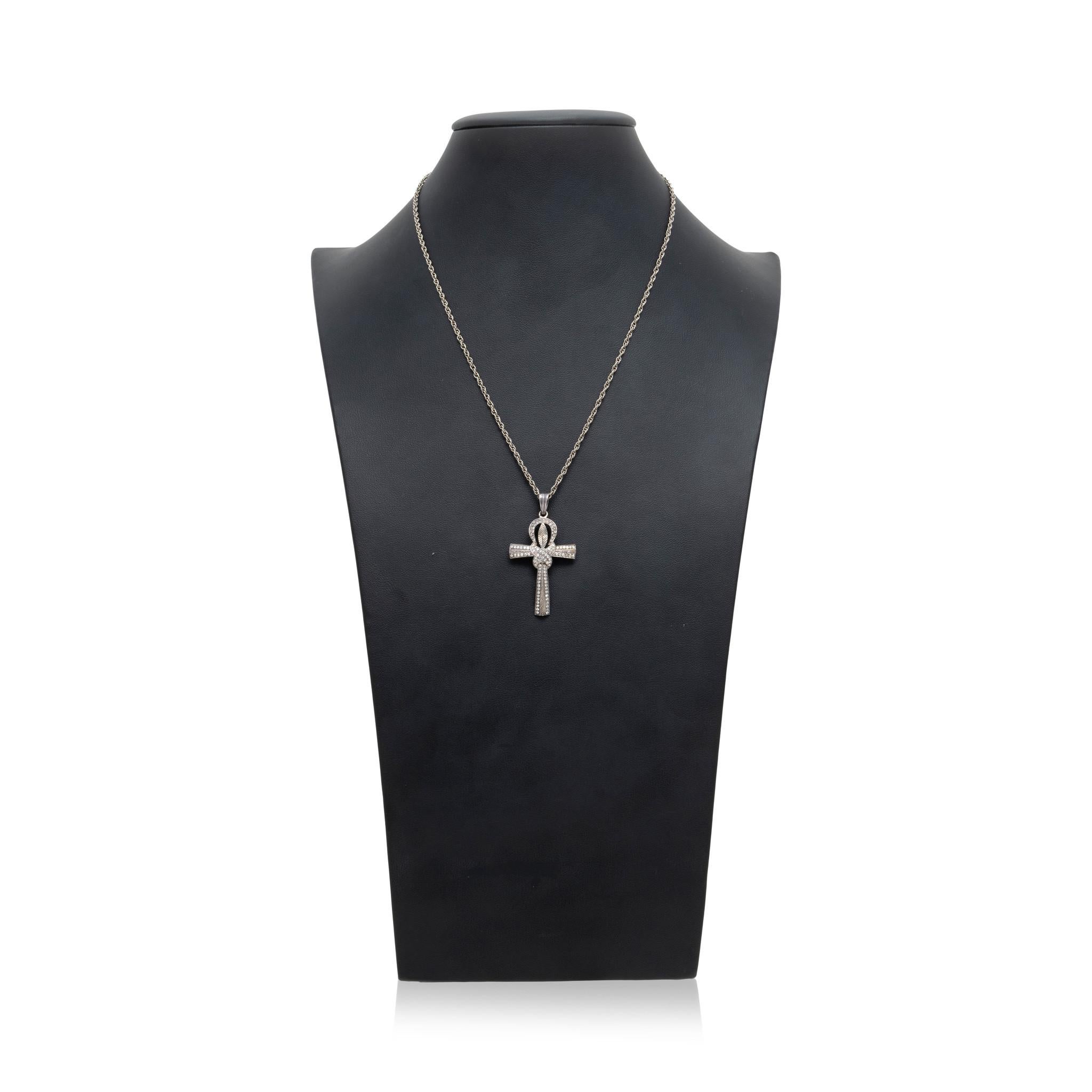 Ciondolo a forma di croce in argento e diamanti. Caratterizzato da un design annodato in stile anubiano con un totale di 82 piccoli diamanti rotondi lungo la superficie per un peso di circa 79cttw. Al centro del nodo c'è un disegno di foglie inciso.
