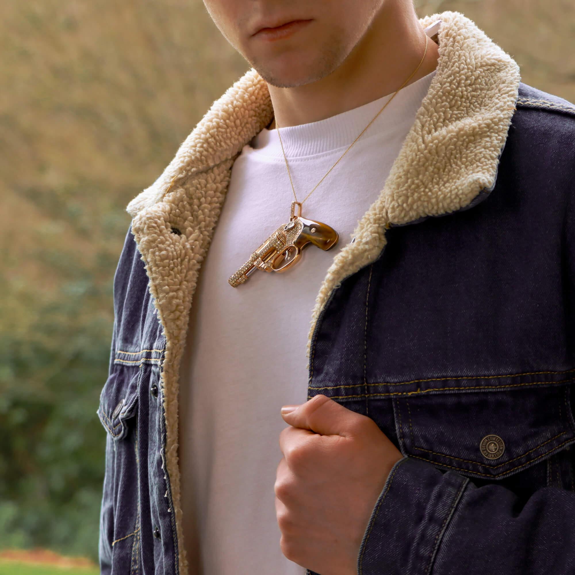 An exquisite diamond and tiger's eye revolver pendant in 18 karat rose and white gold. 
Whether you are a fan of James Bond or usually root for the Bond Villain, it is hard to ignore this exquisite jewelled revolver pendant as a wardrobe accessory.