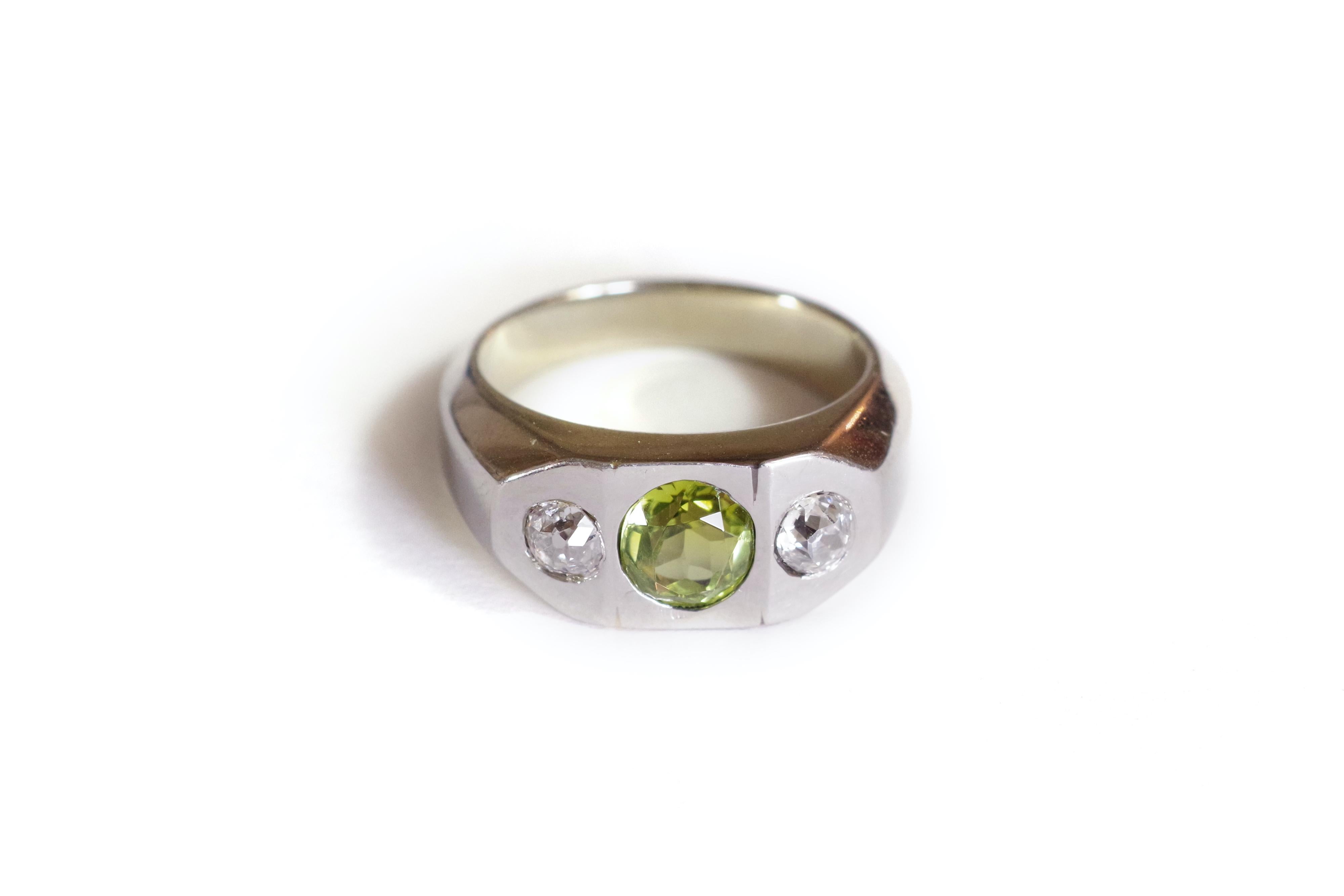 Diamond and tourmaline signet ring in 18k white gold. In the center, an oval green tourmaline, also called verdelite, framed by two European old cut diamonds. The three gems are set in a large ring with geometric lines, displaying modernist lines.