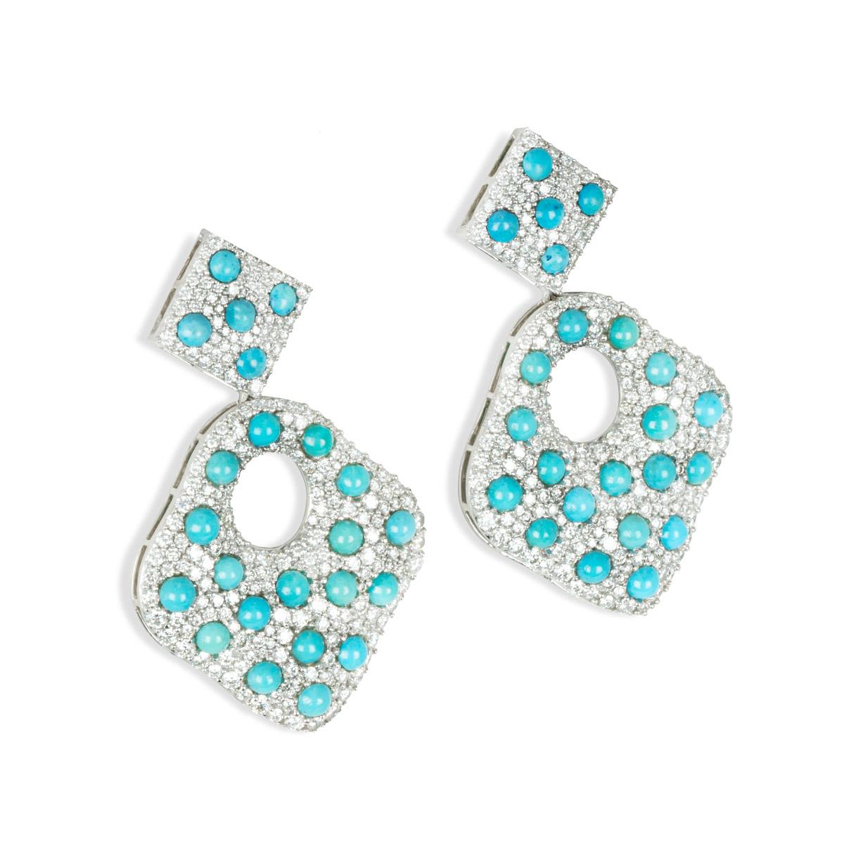 A pair of 18k white gold diamond and turquoise drop earrings. The earrings feature 2 rhombus shapes suspended from one another with an oval opening. There are 485 pave set round brilliant cut diamonds totalling 6.02ct, G-H colour and VS clarity and