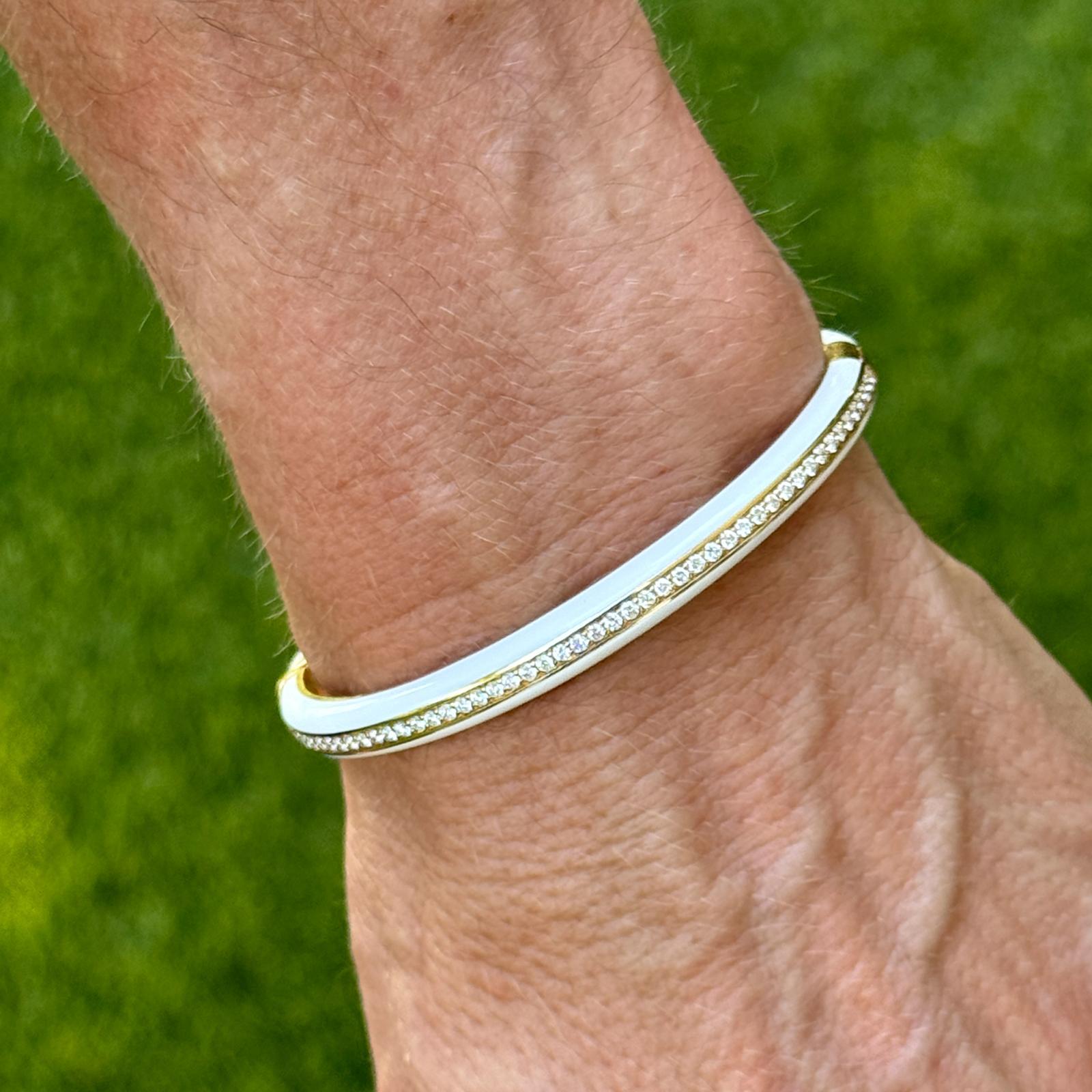 La sophistication moderne rencontre le luxe intemporel dans ce remarquable bracelet à charnière en or jaune 18 carats. Conçu dans une forme ovale élégante pour convenir aux poignets jusqu'à 6,5 pouces, le bracelet présente une rangée centrale de 100