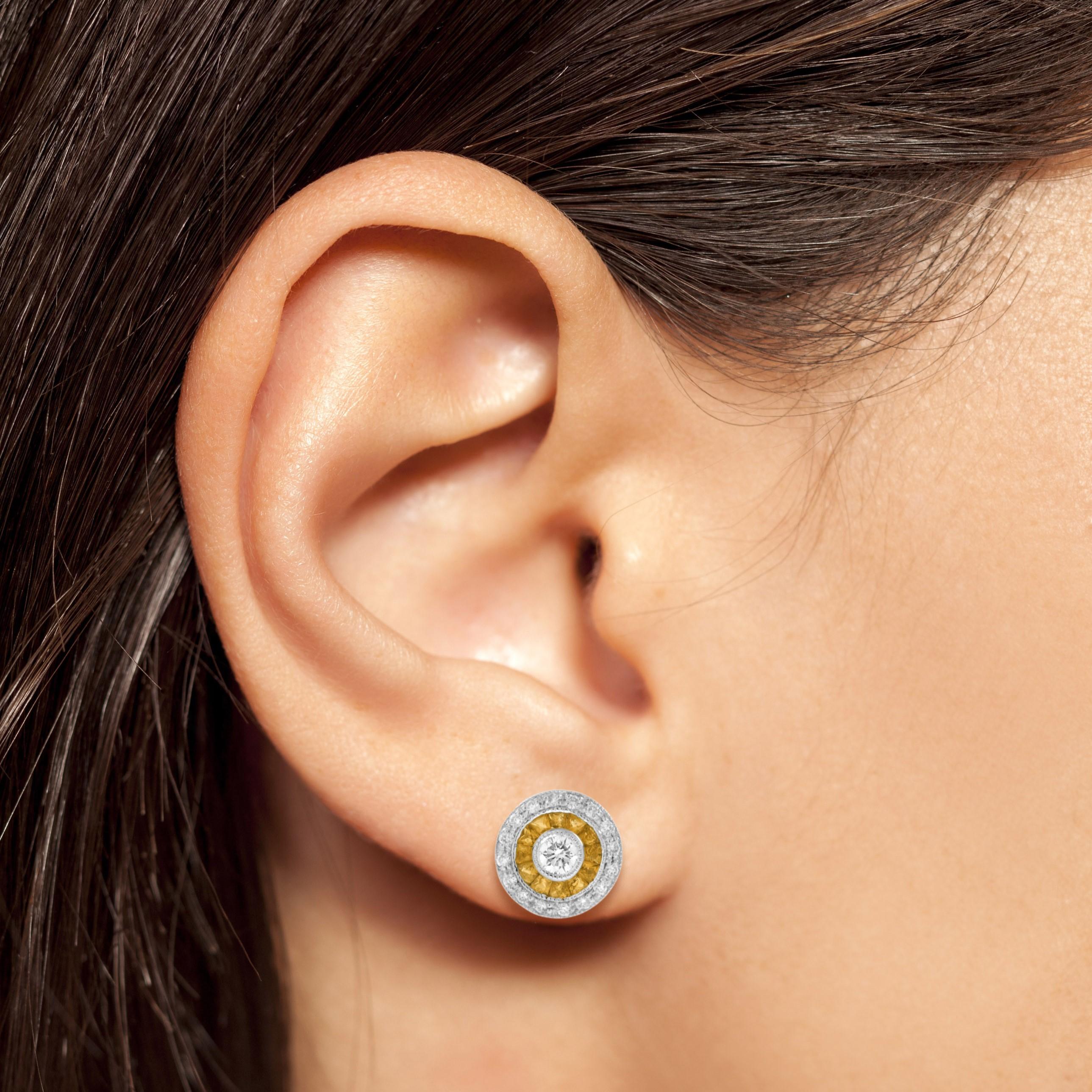 This Art-Deco stud earrings are completely spectacular! The vibrant color stone of yellow sapphire are specialty cut to surround the excellent round brilliant cut center diamond, which is in a thin bezel with mil-grain detail. Crafted in 18k two