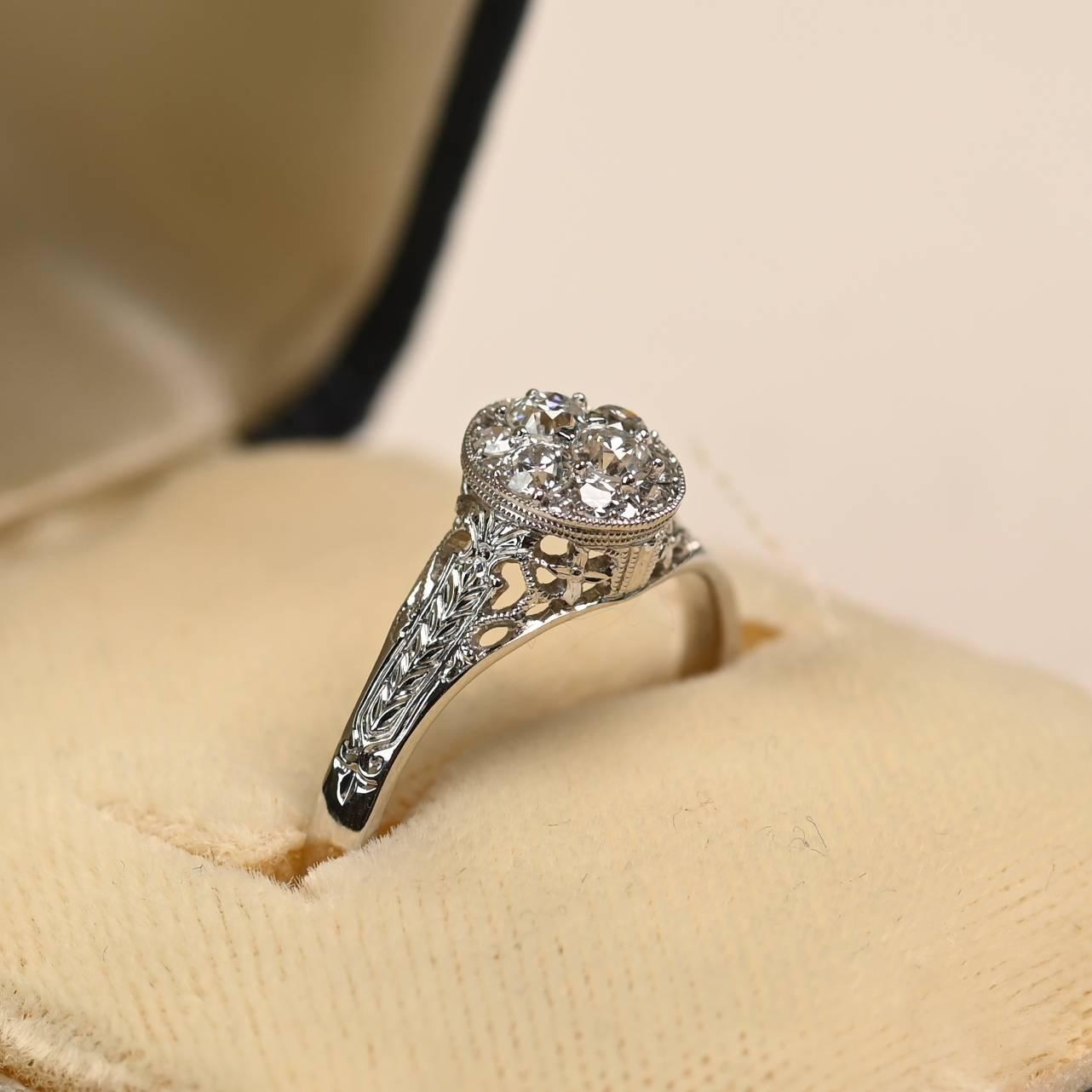 Cette charmante bague d'inspiration vintage présente une grappe de diamants centrale d'un poids total d'environ 0,30 carat, sertie dans une monture à pinces partagées. La grappe est encadrée par une élégante lunette ovale aux fins détails de