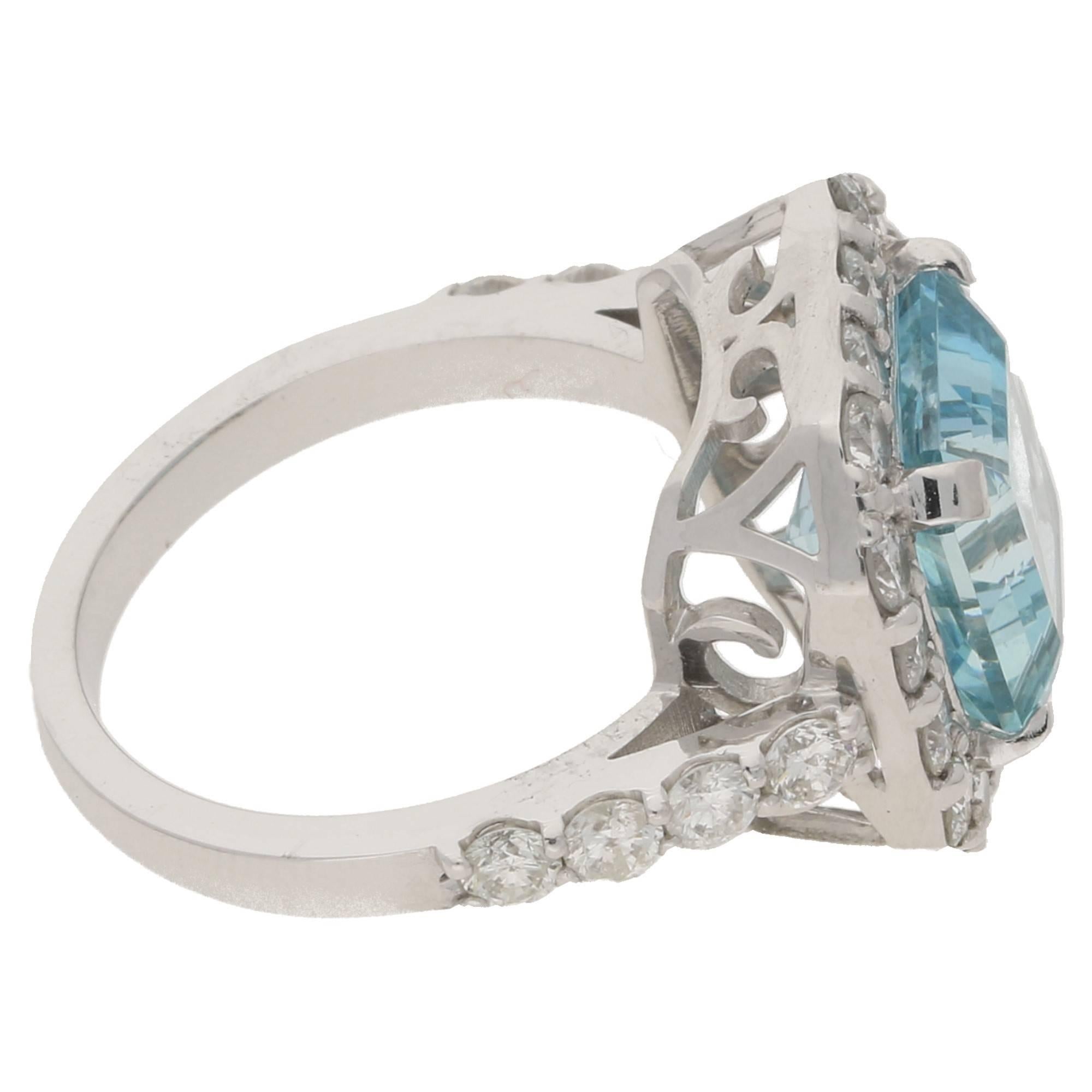 A striking modern aquamarine and diamond cluster ring in 18ct white gold. The ring is formed of a square emerald cut aquamarine elegantly set with four corner claws, surrounded with sixteen round brilliant cut diamonds. Each drop down shoulder is