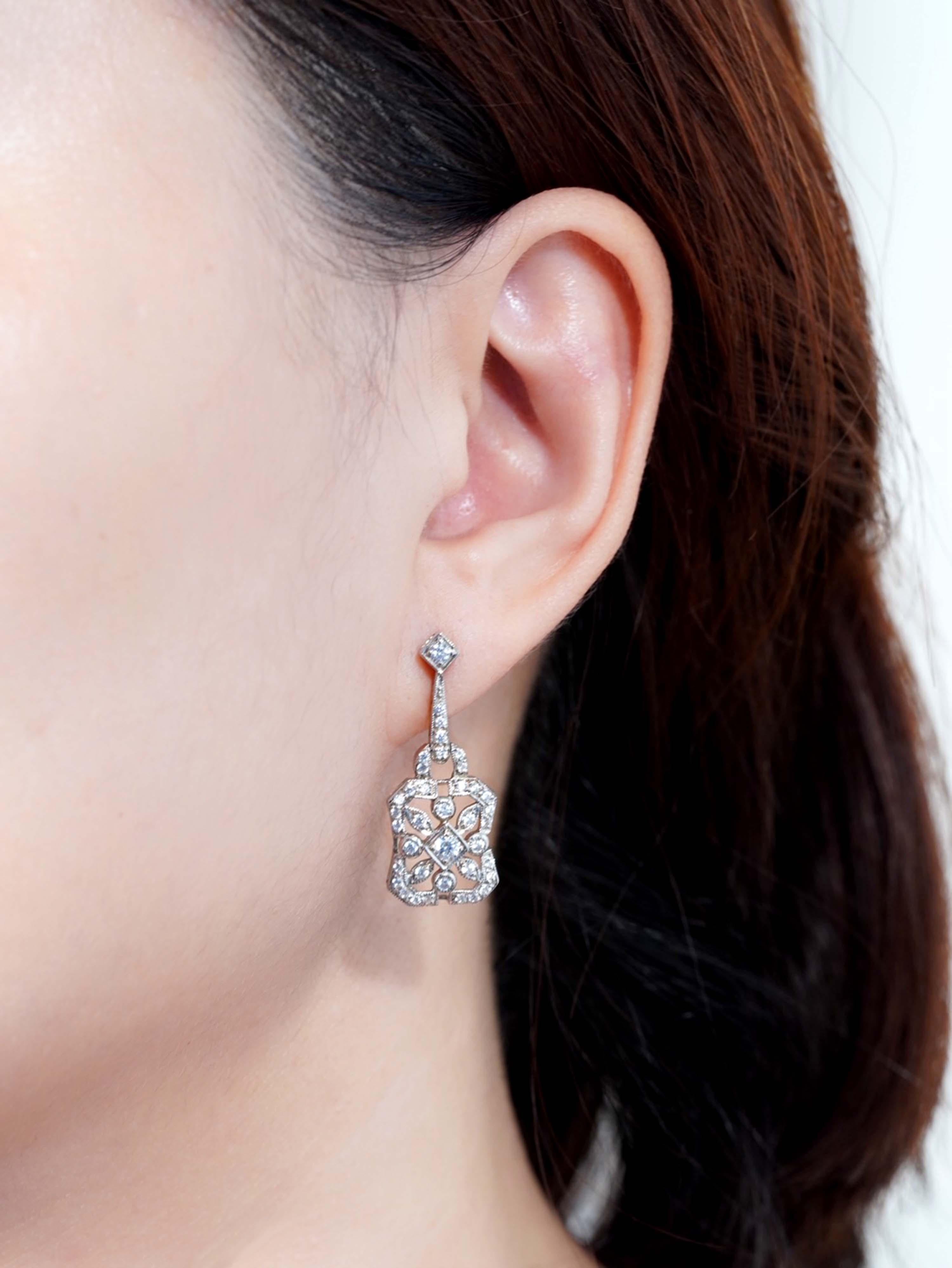 Inspired by Art Deco elegance, these antique-style floral earrings feature a captivating round diamond at the center, symbolizing the heart of a blooming flower. Petal-like diamond accents surround the centerpiece in a graceful floral motif, echoing