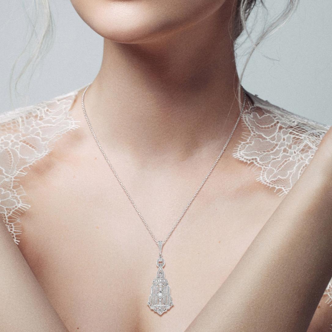 Graceful and sophisticated, this 14k white gold necklace boasts a shimmering Art Deco inspired pendant adorned with a unique design of round and baguette diamonds, finished with a sparkling diamond bail. 

Information
Style: Art Deco
Metal: 14K