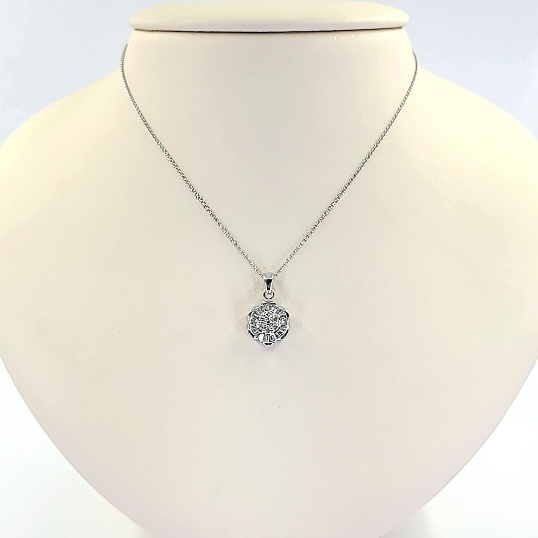 18 Karat White Gold Flower Pendant Necklace Featuring 31 Baguette and Round Brilliant Cut Diamonds of SI Clarity and G Color Totaling Approximately 0.64 Carats. 16 Inches Long. Finished Weight Is 3.7 Grams.
