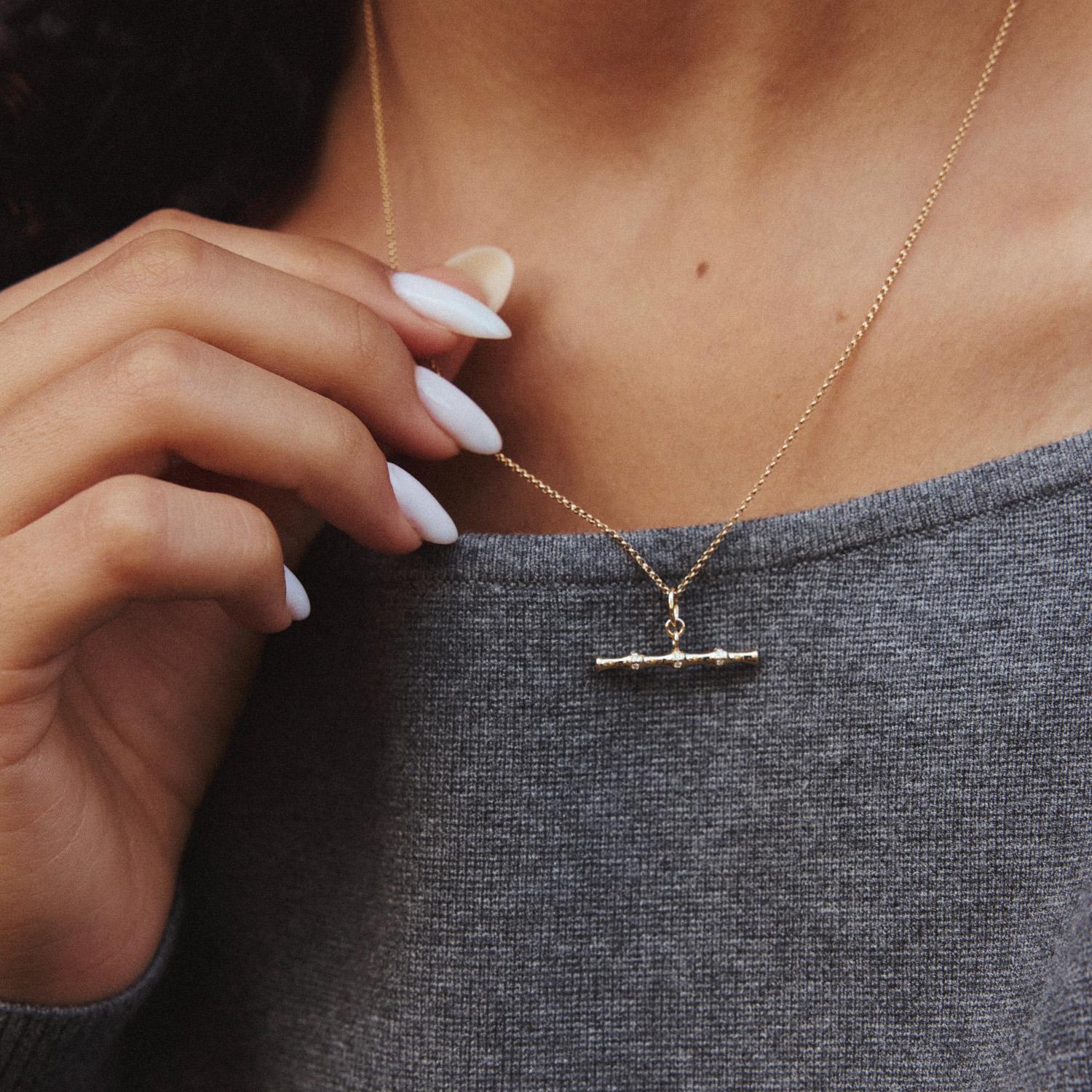 Rappelant les chaînes de montre à barre en T de l'époque victorienne, cet étonnant pendentif à barre en T de 23 mm de large est composé de sections de faux bambou en or jaune 14 carats entre lesquelles se trouvent des diamants ronds. Le pendentif