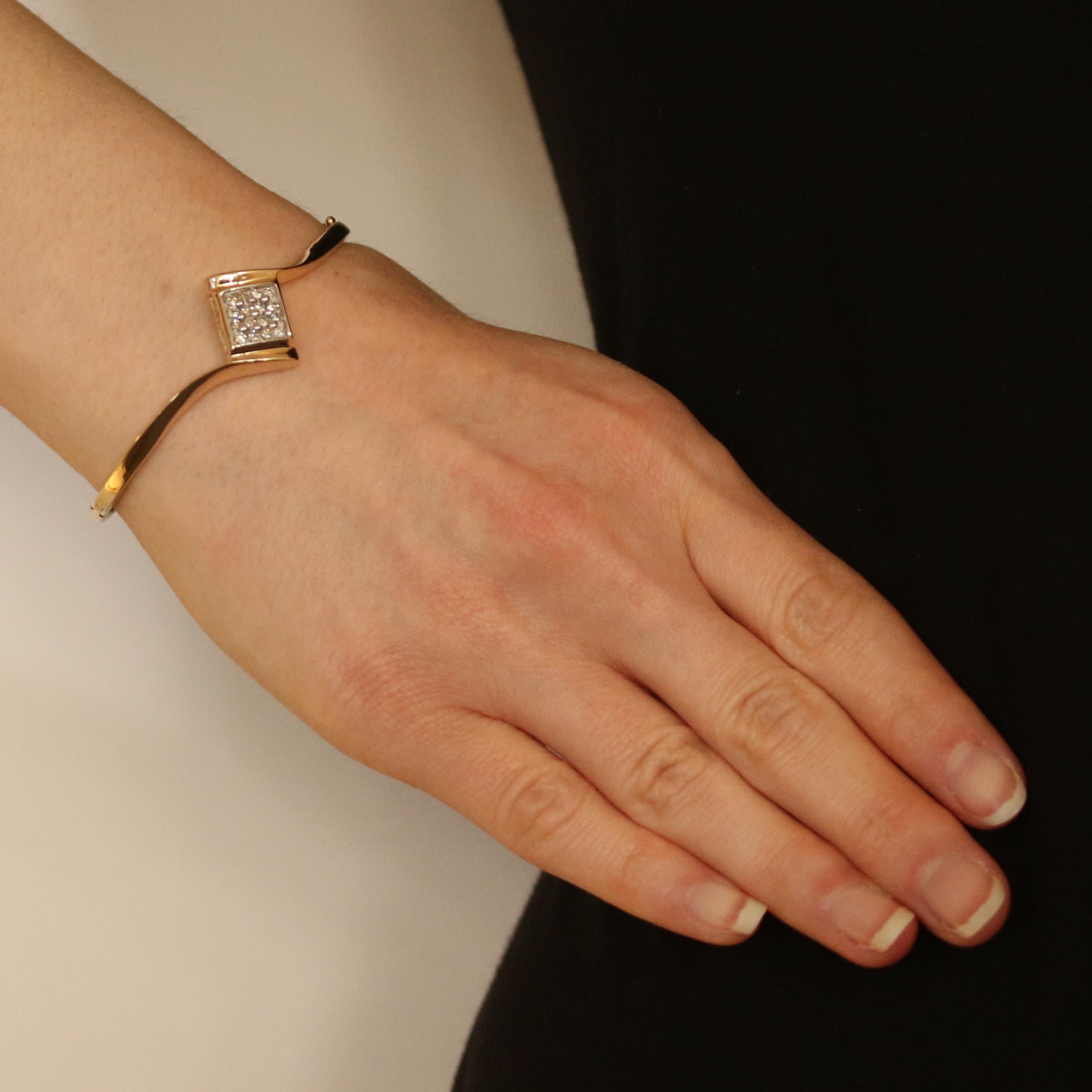 Beschenken Sie sie dieses Jahr mit funkelnden Diamanten! Dieses Armband aus 10 Karat Gelbgold im schmeichelhaften Armreif-Stil zeigt ein anmutiges Bypass-Design mit einem strahlenden Diamantencluster in einem Rahmen aus 10 Karat Weißgold. 
 
