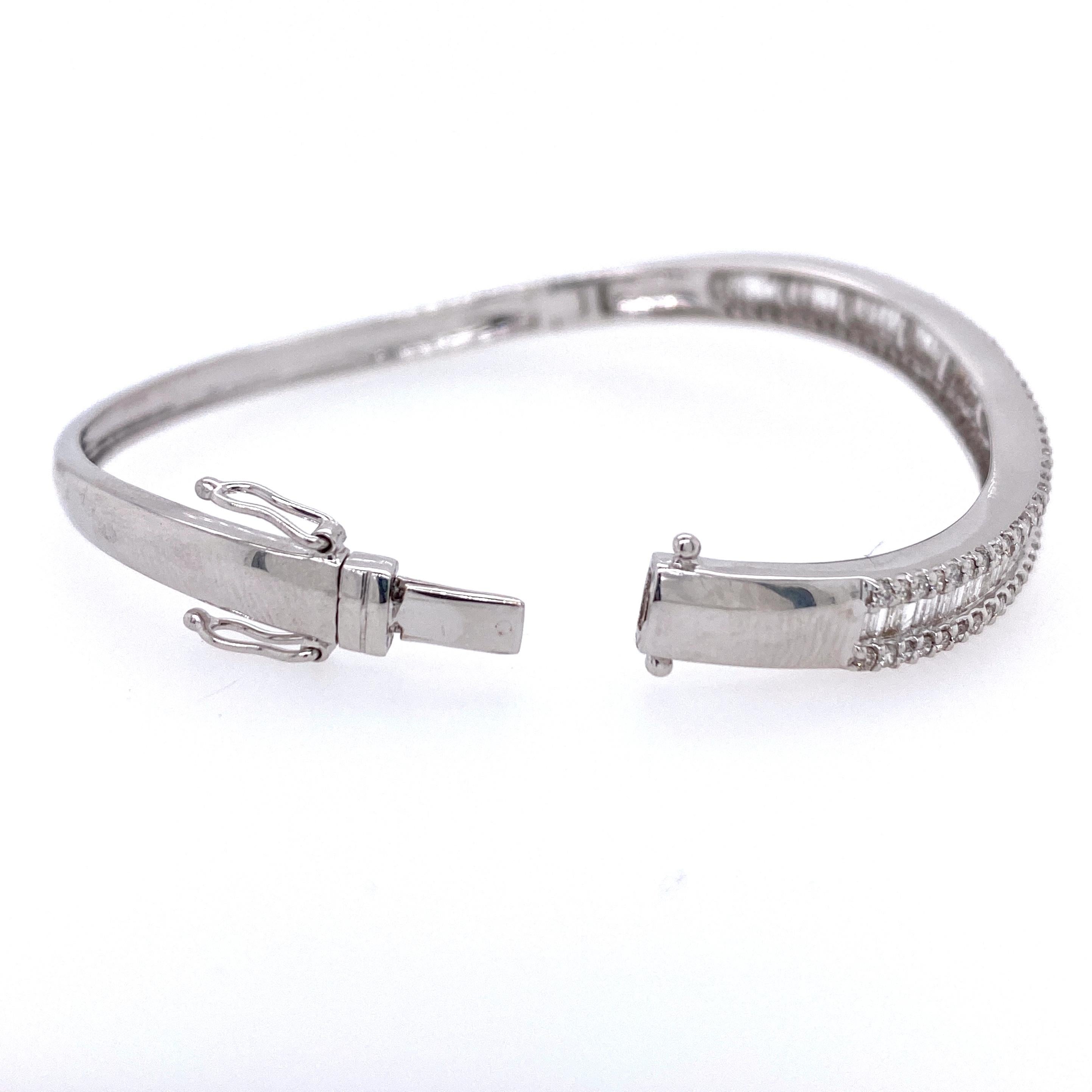 One 14 karat white gold (stamped 14K) bangle bracelet set with fifty-nine straight baguette diamonds and eighty-two round brilliant diamonds, approximately 3.00 carats total weight with matching H/I color and I1 clarity.  The top of the bracelet